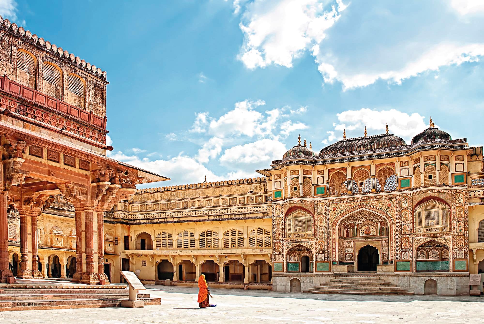 A person in an orange robe in the middle of the courtyard at Amber Fort in Jaipur, India.