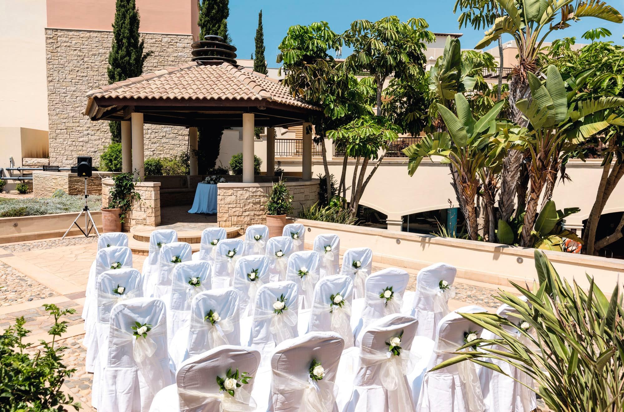 A wedding ceremony set-up on a sunny stone terrace.