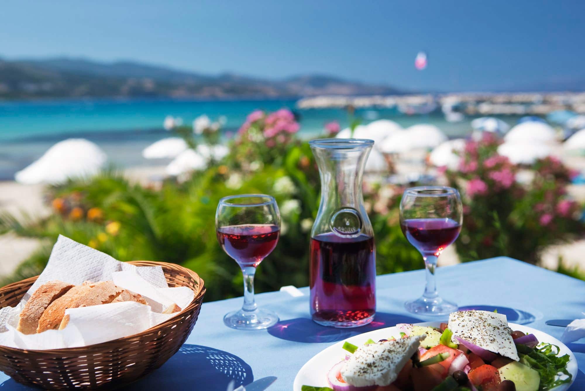 A table laid out with Mediterranean food in front of the sea.