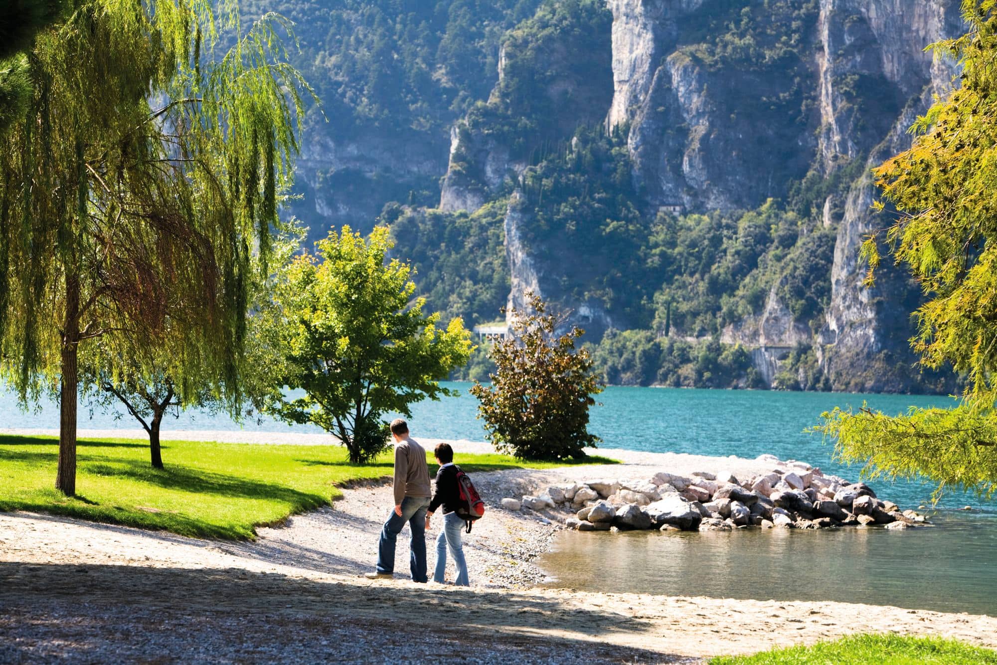 Two people walking along the lakeside in Riva, Lake Garda.