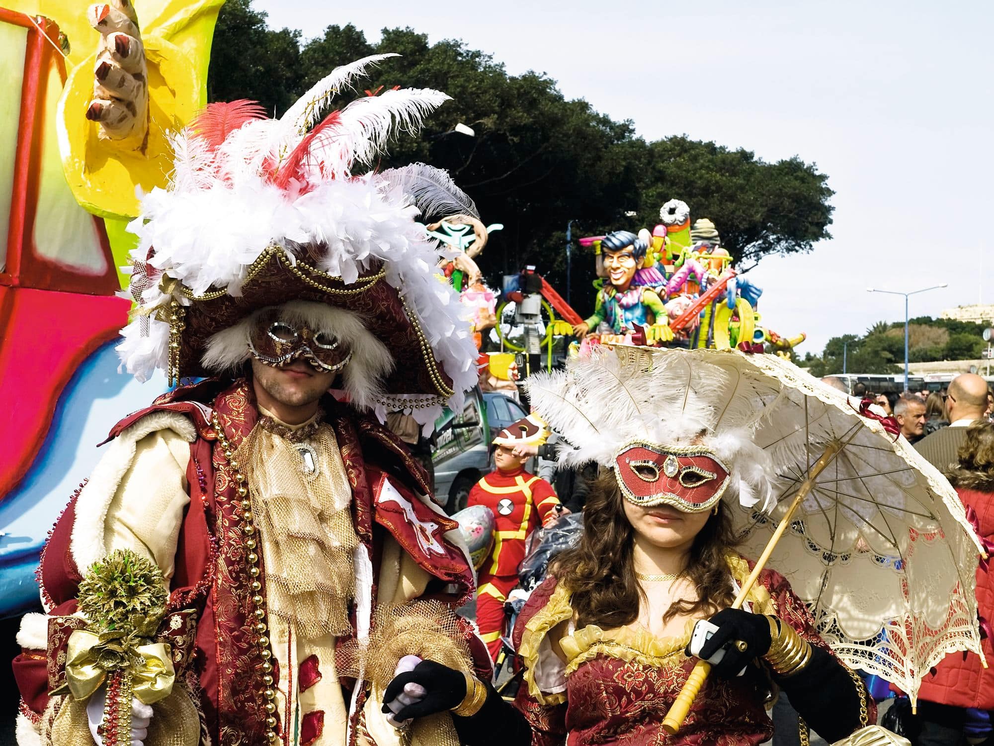 People in elaborate masks and costumes at a colourful carnival parade.