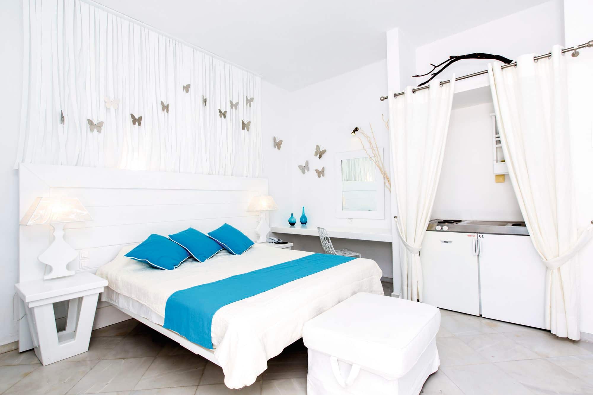 A double bed with blue pillows and runner.