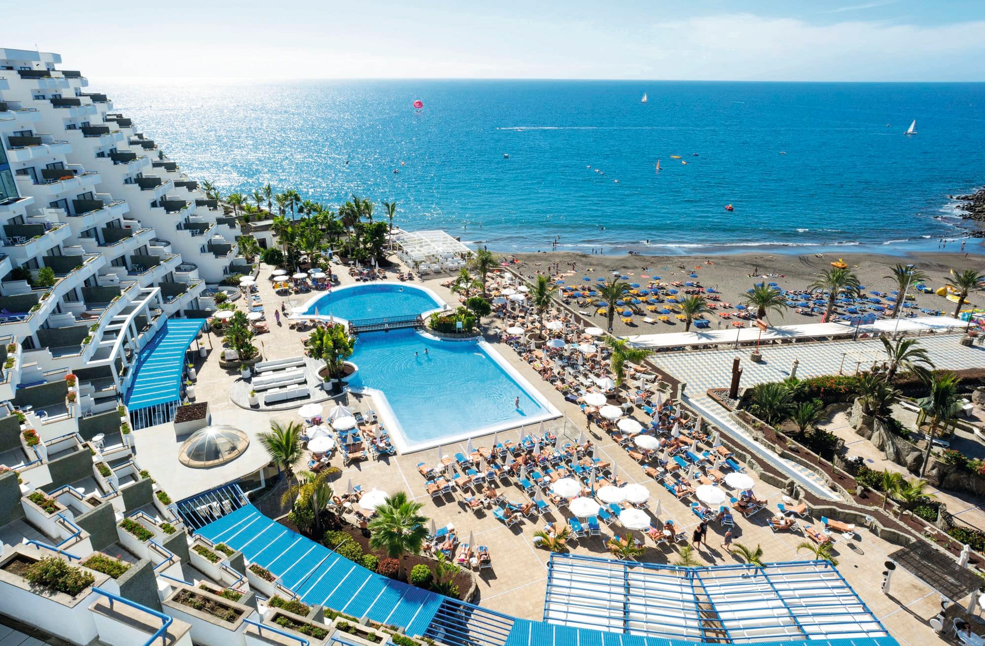 A view of the surrounding pool and beach area from a hotel exterior.