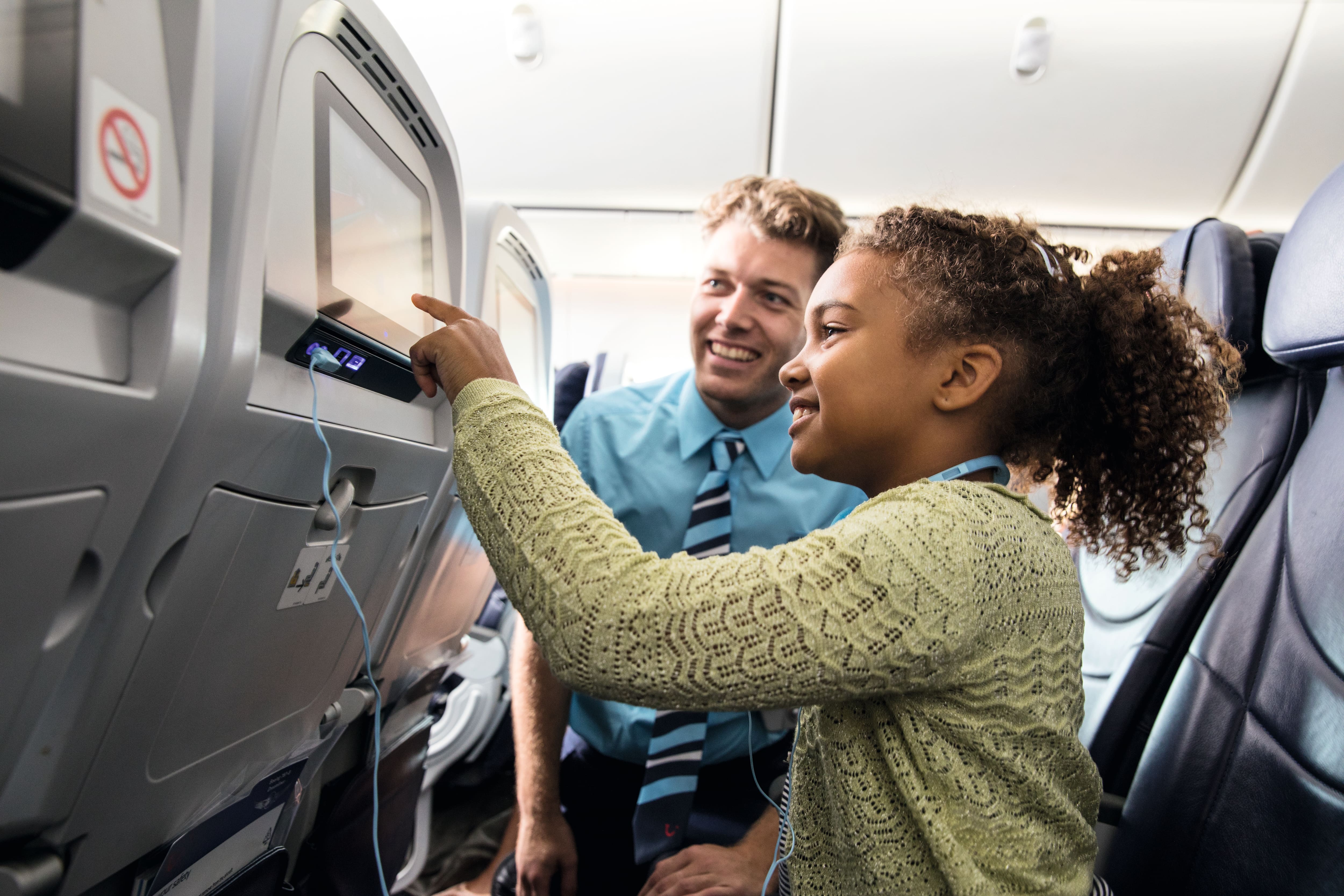 TUI cabin crew helping a child with the in-flight entertainment.