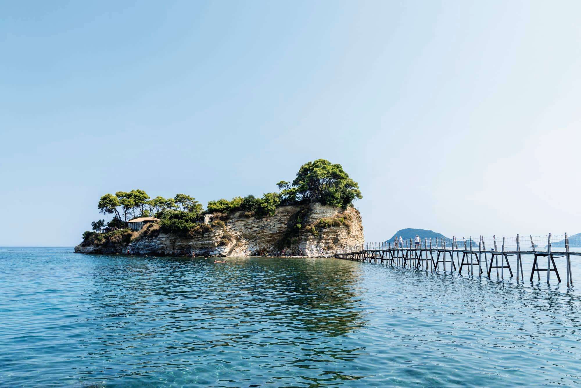 A boardwalk leading to a rocky island with a beach.