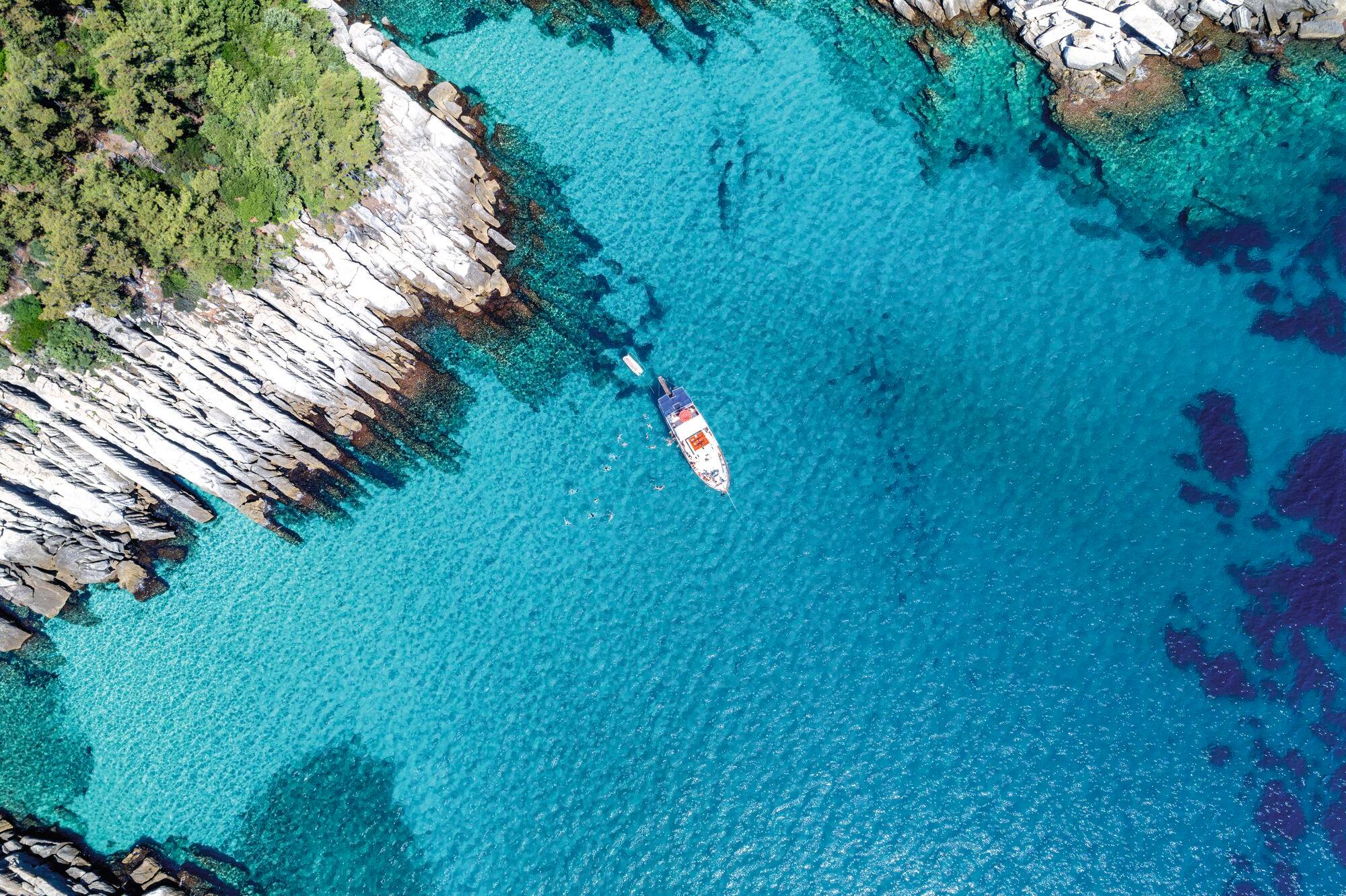 An aerial view of a boat sailing on the coast of Thassos