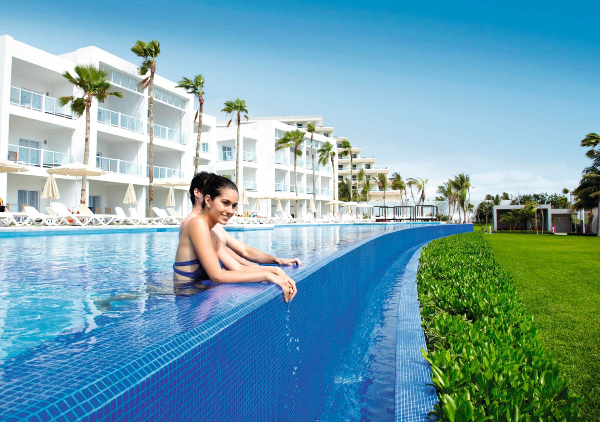 Couple relaxing in an infinity pool at a luxury tropical resort.