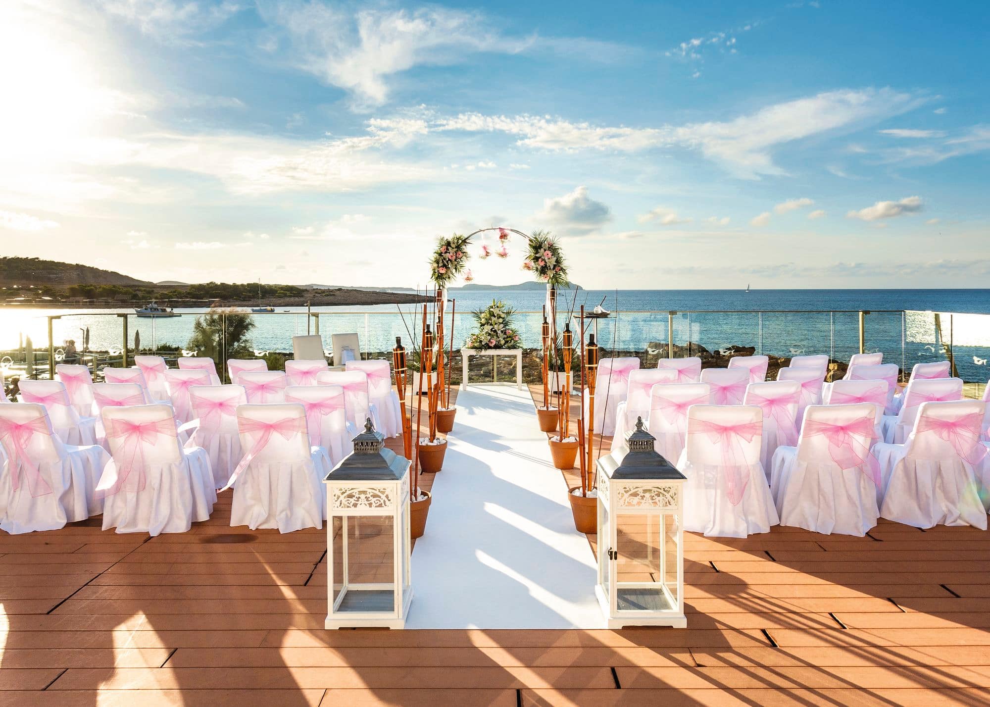 An outdoor seafront wedding ceremony setup on a wooden deck.