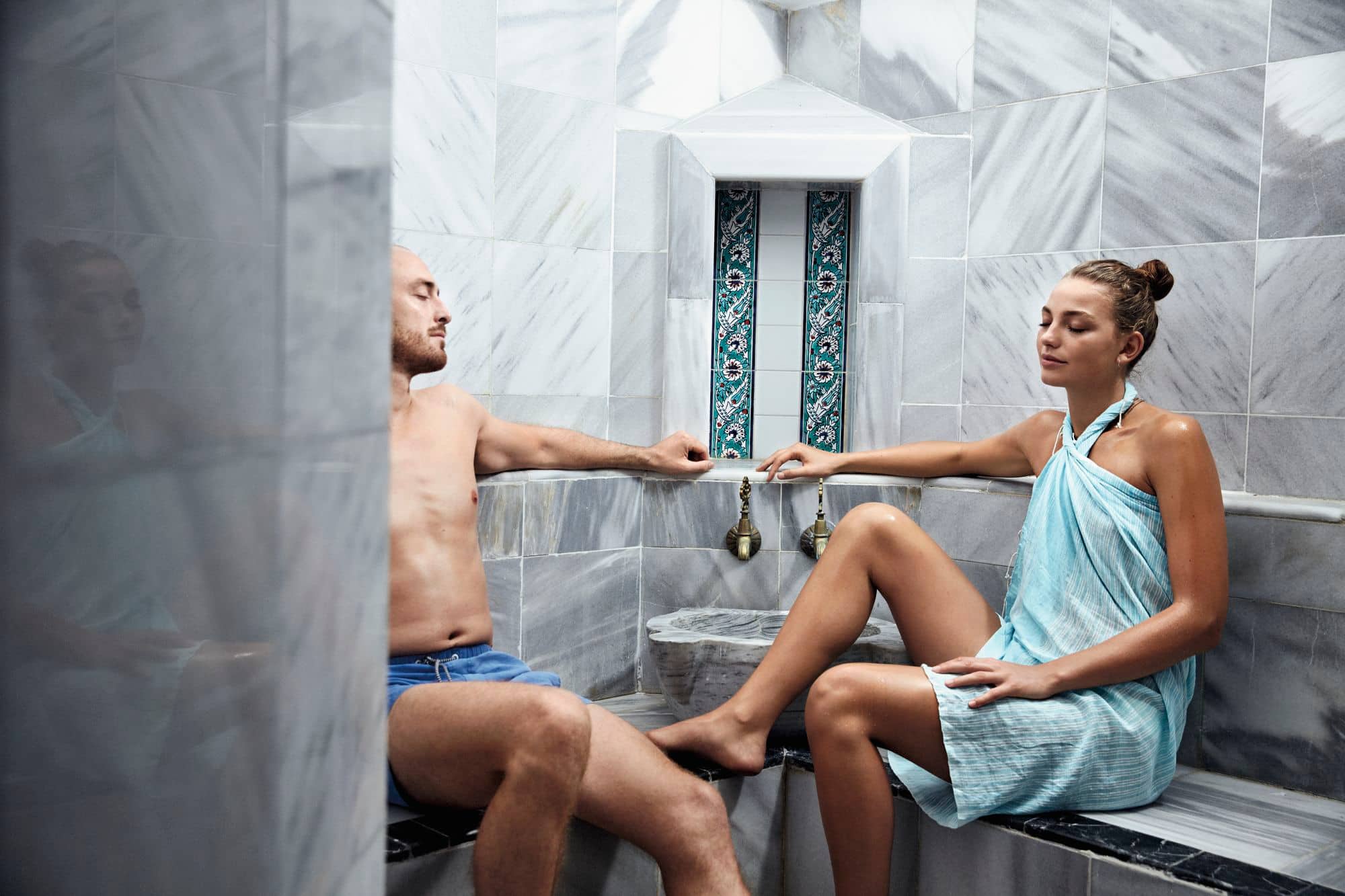 A coupe relaxing in a marble sauna.