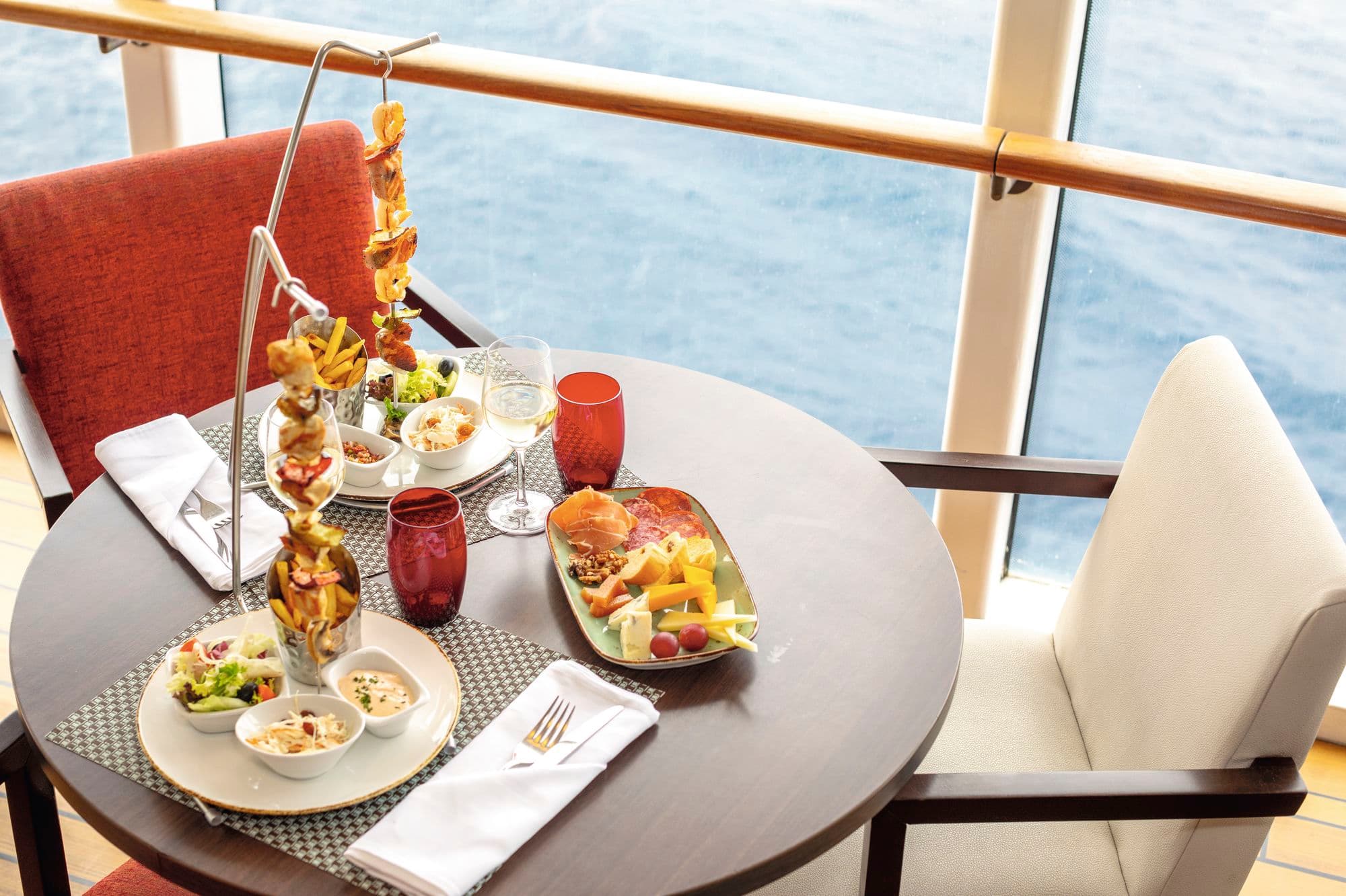 Food arranged on a table at a sea-view balcony.