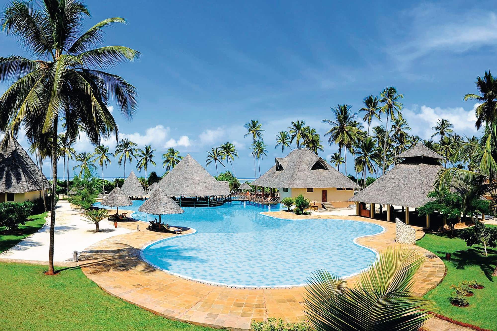 The pool and surrounding beach huts at Neptune Pwani Beach Resort & Spa.