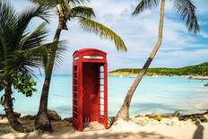A red British-style telephone booth on a tropical beach