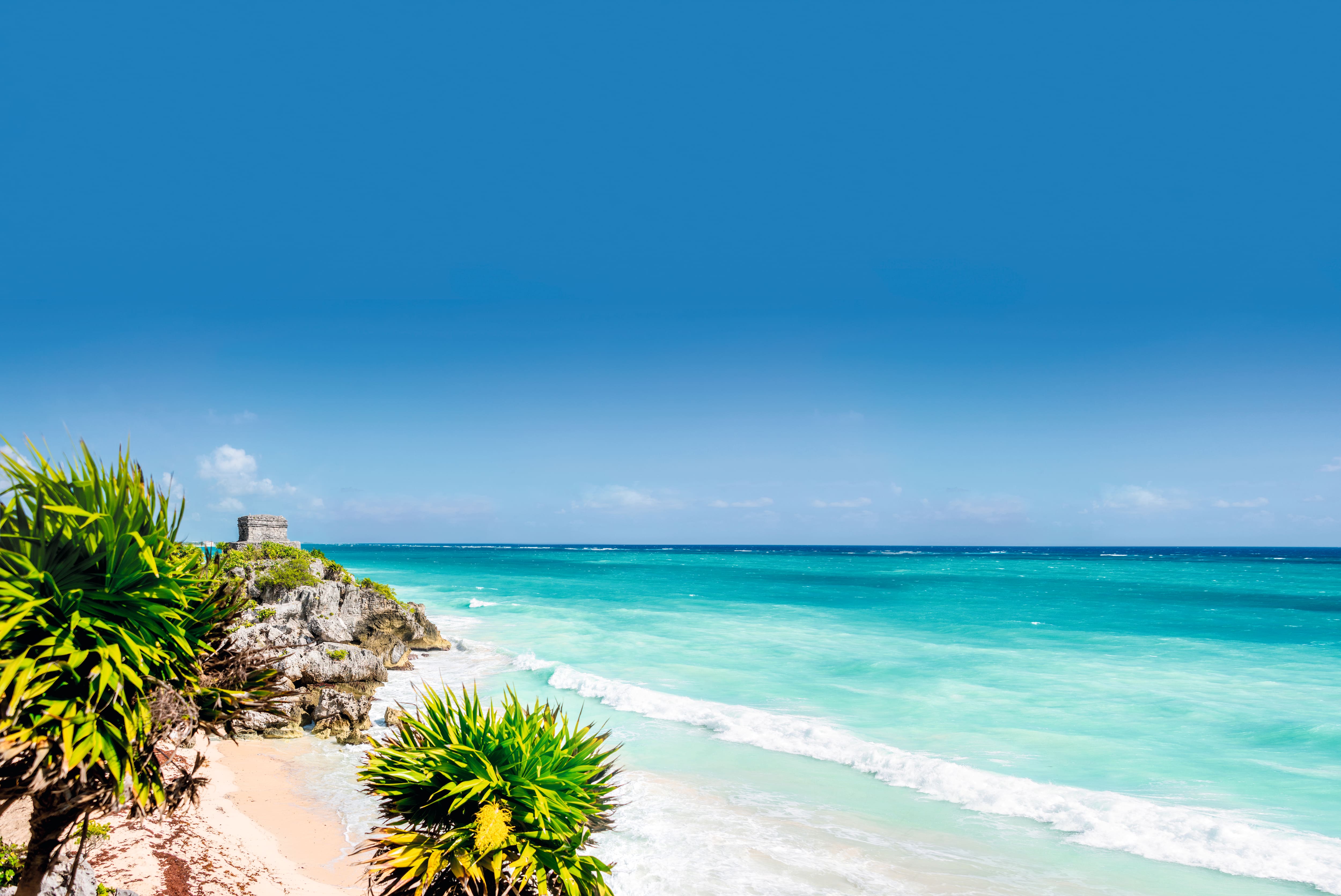 A view of a stone structure on a cliff, overlooking a beach in Mexico.