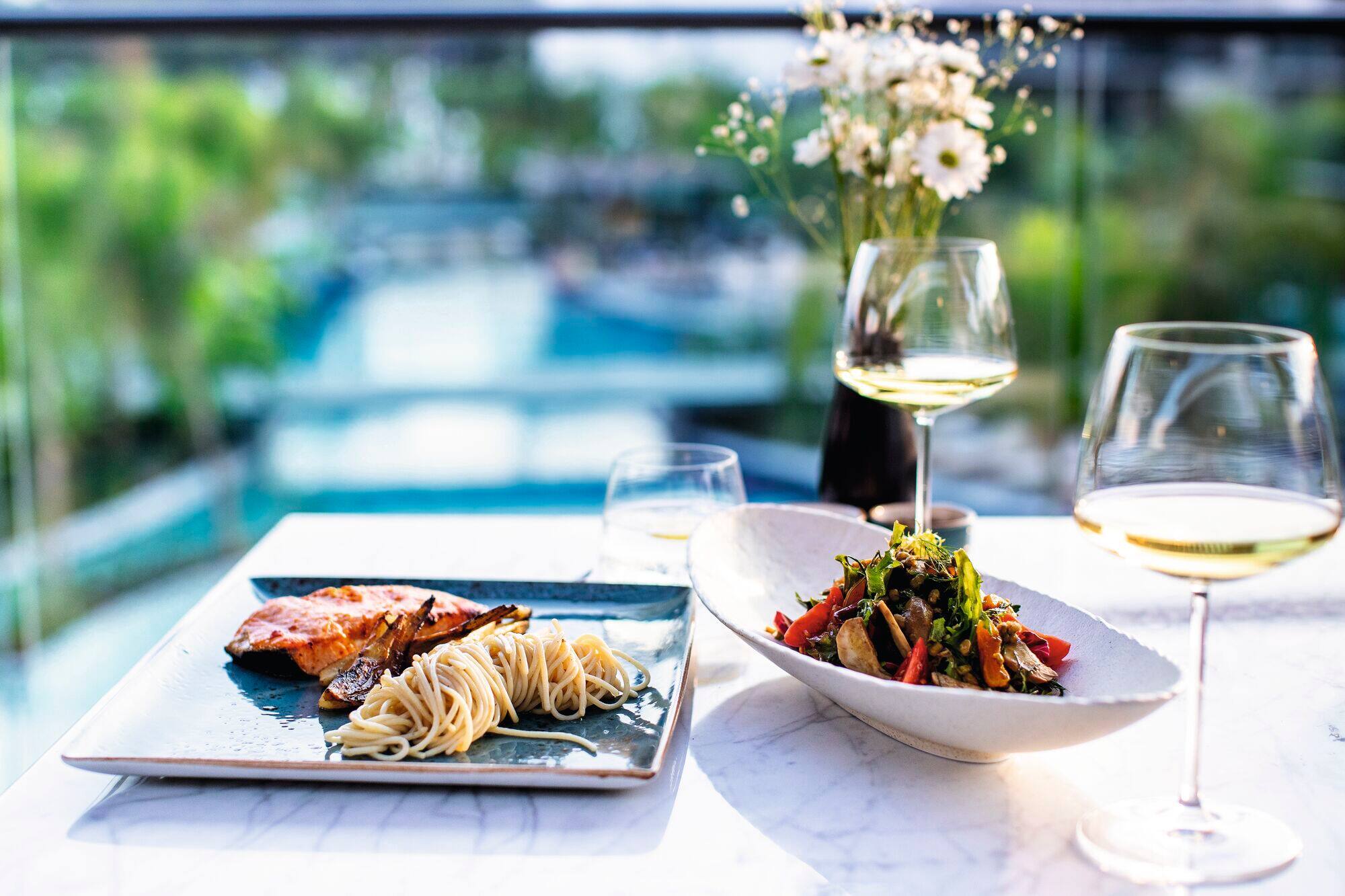 Upscale outdoor dining scene on a white marble table showcasing two courses.