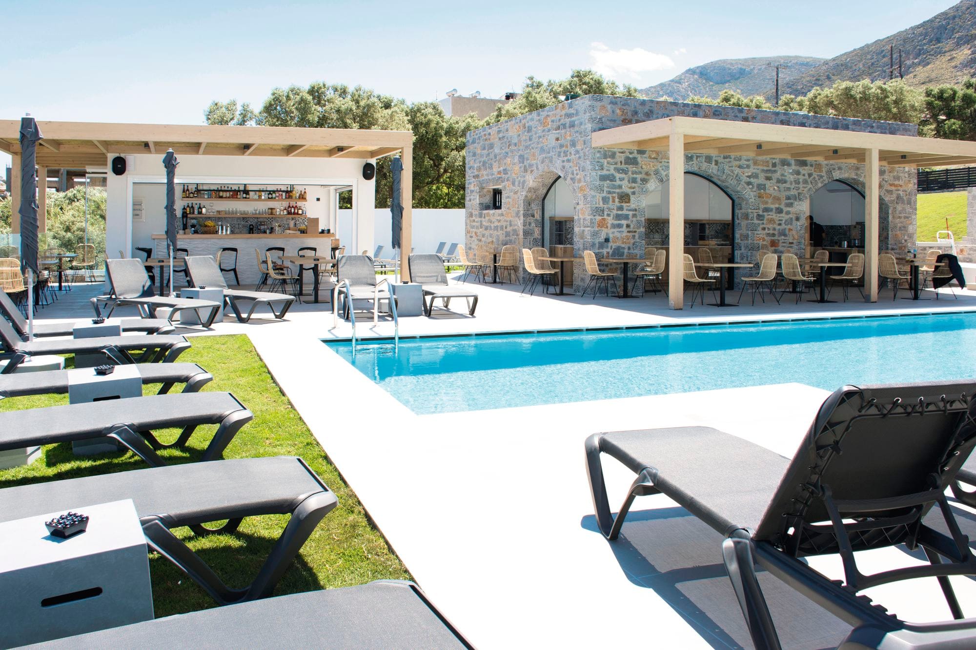 A swimming pool with a mountain view and nearby pool bars.