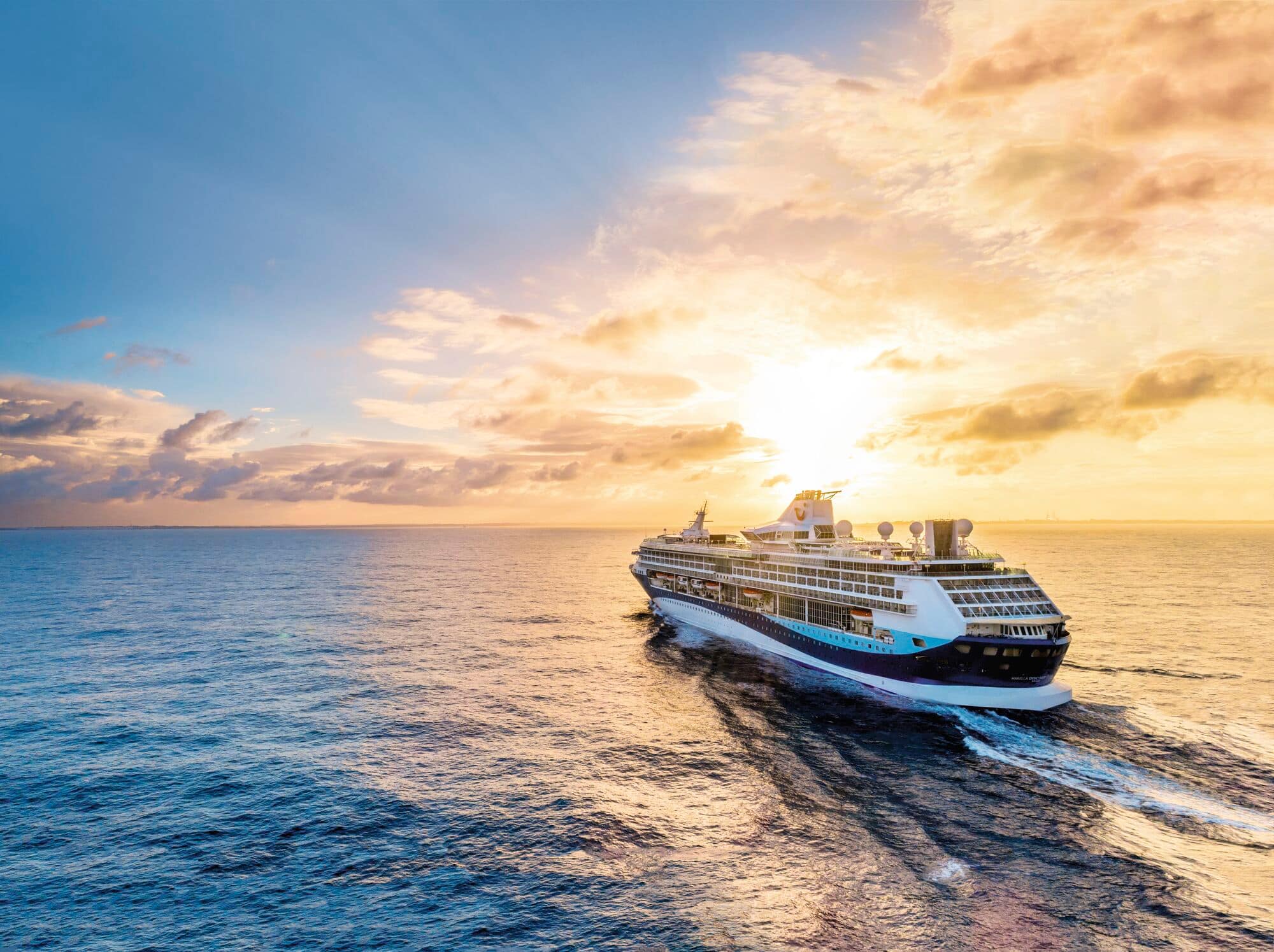 An aerial view of Marella Discovery 2 sailing towards a sunset.