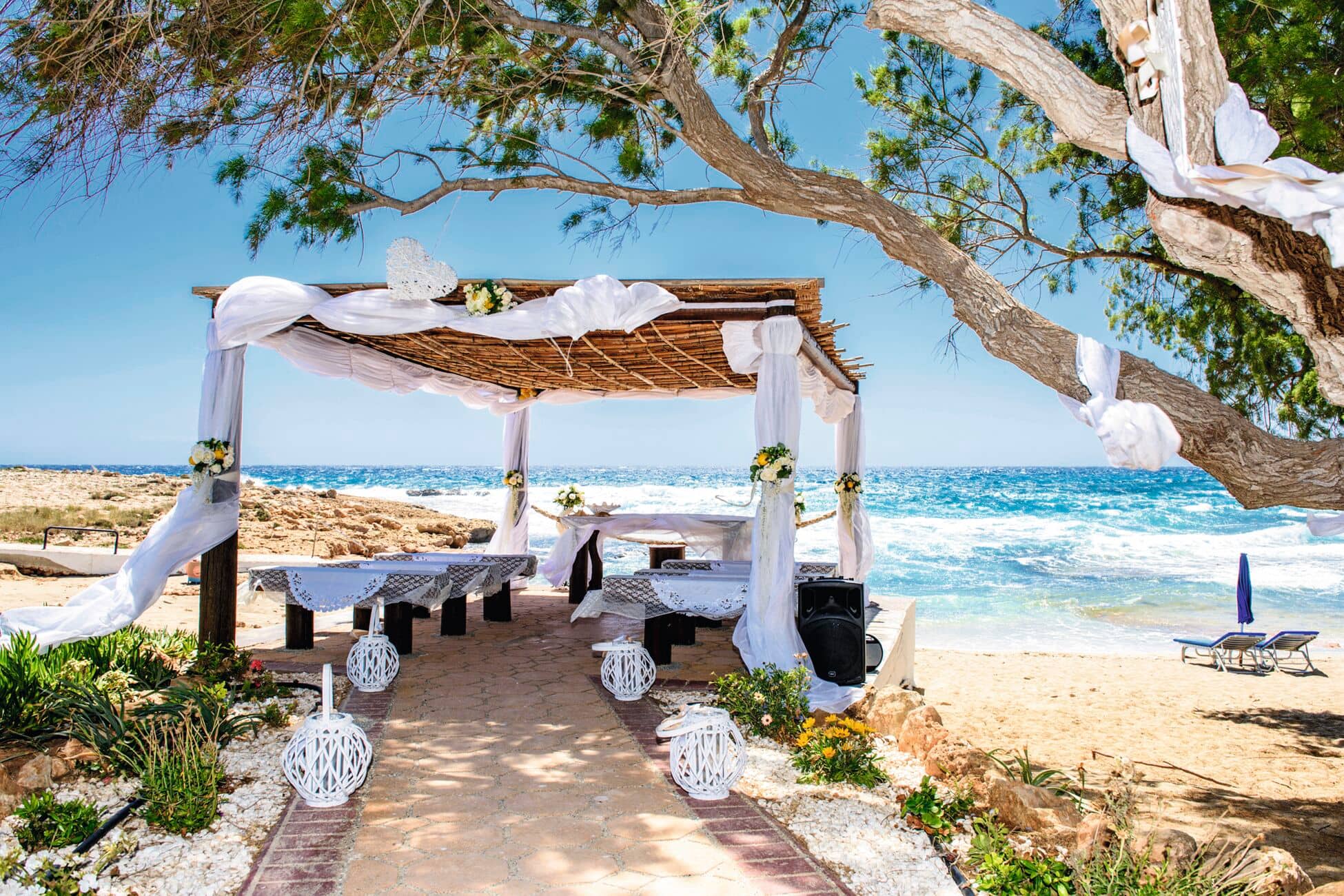 A dreamy beach wedding ceremony setup with flowing drapes, fresh florals and ocean views.