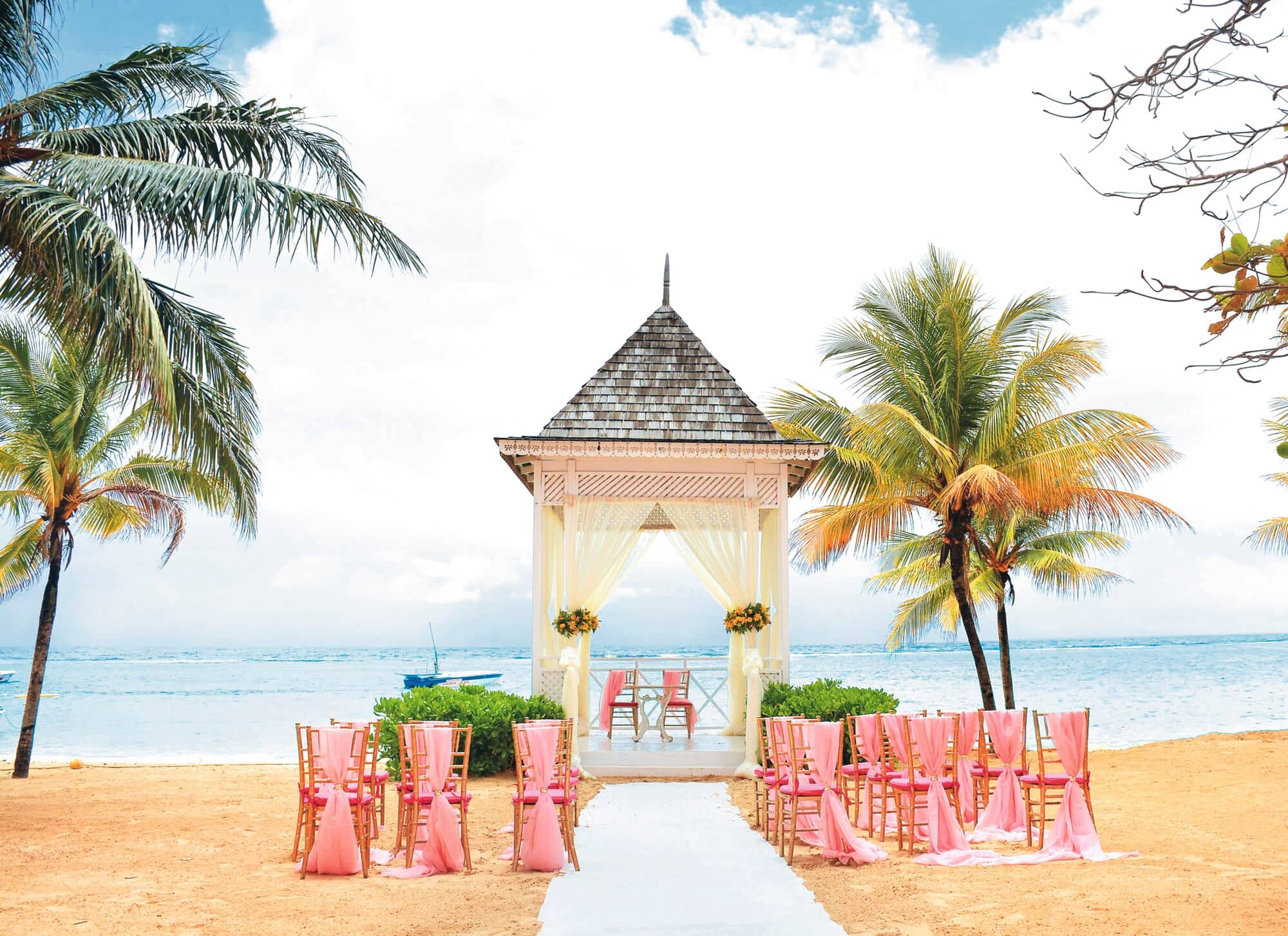 A beach wedding gazebo and rows of chairs look out to sea.