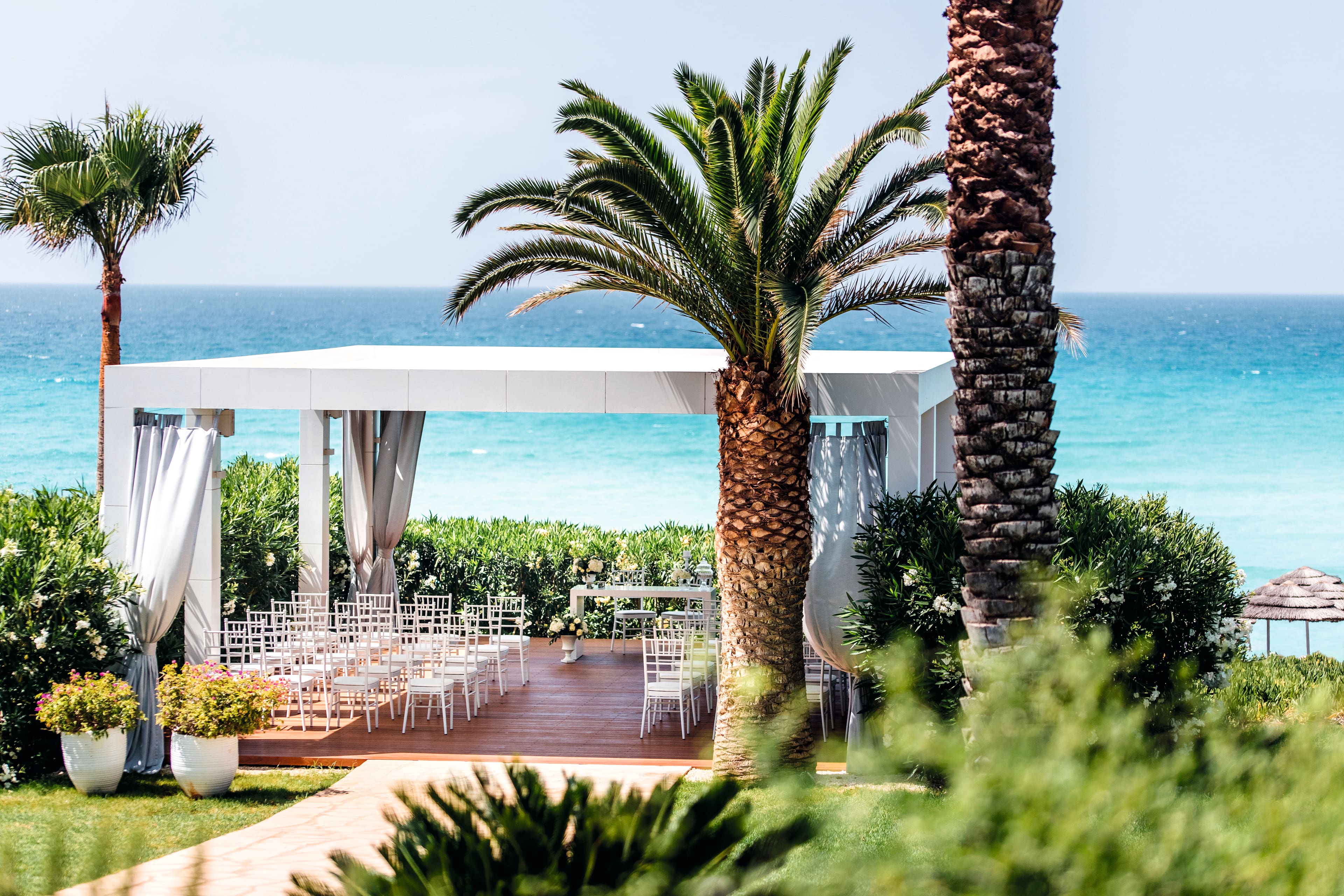 Looking down toward a covered wedding arrangement. An elegant, minimalist setup sits beneath a white, modern gazebo.
