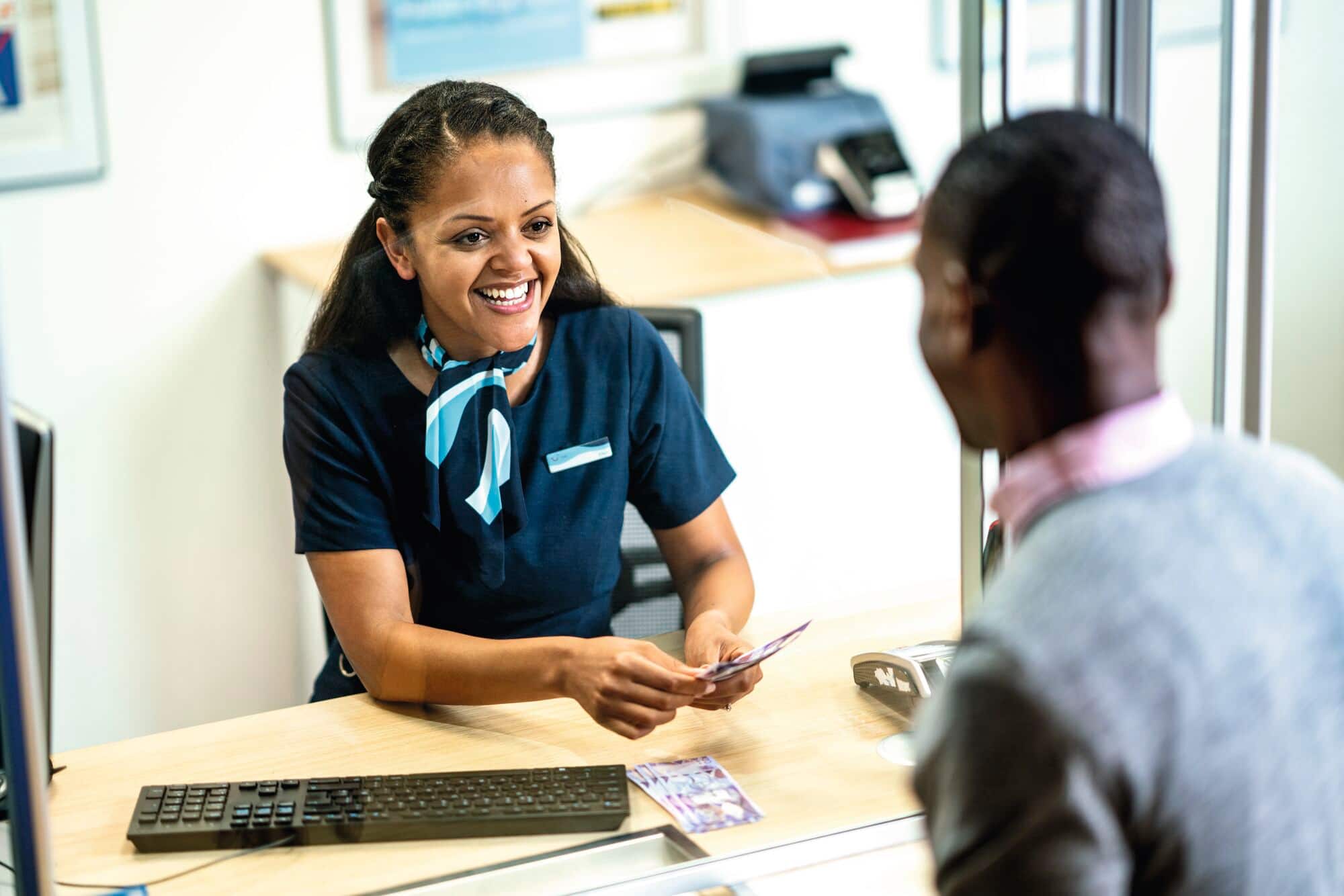 A retail colleague exchanging travel money for a customer in a TUI store.