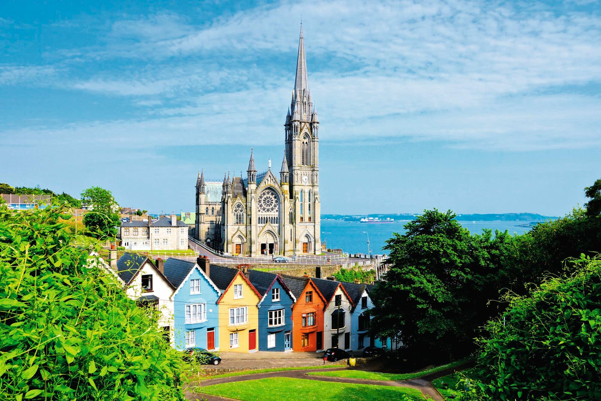 Colourful row of houses with a cathedral in background in the port town of Cobh, County Cork, Ireland. 