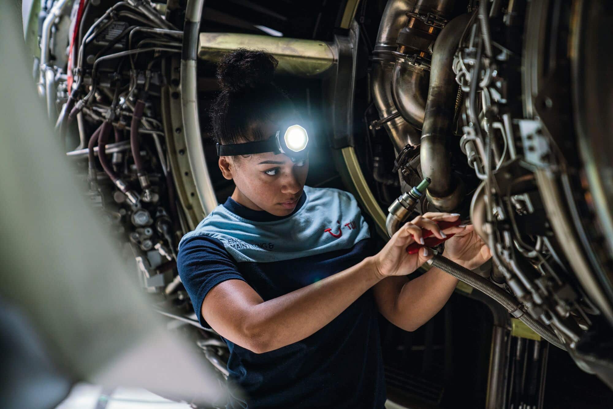 A maintenance team member working on a plane engine in a hangar.