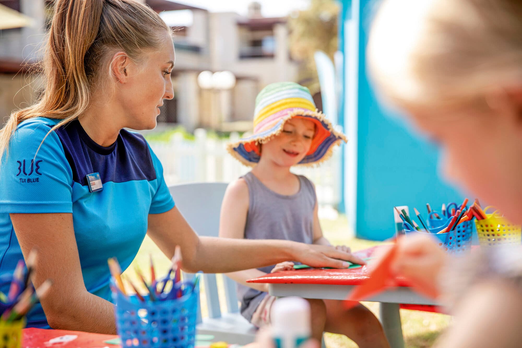 Lady sat helping little girl draw.