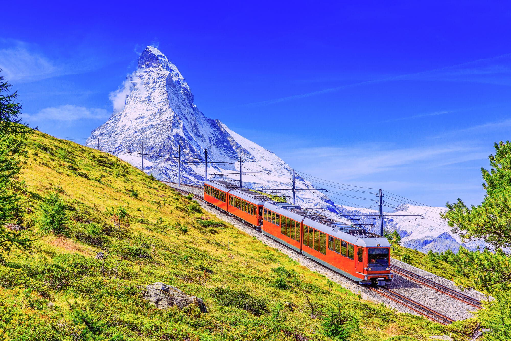 A red train with the Matterhorn mountain in the distance. 