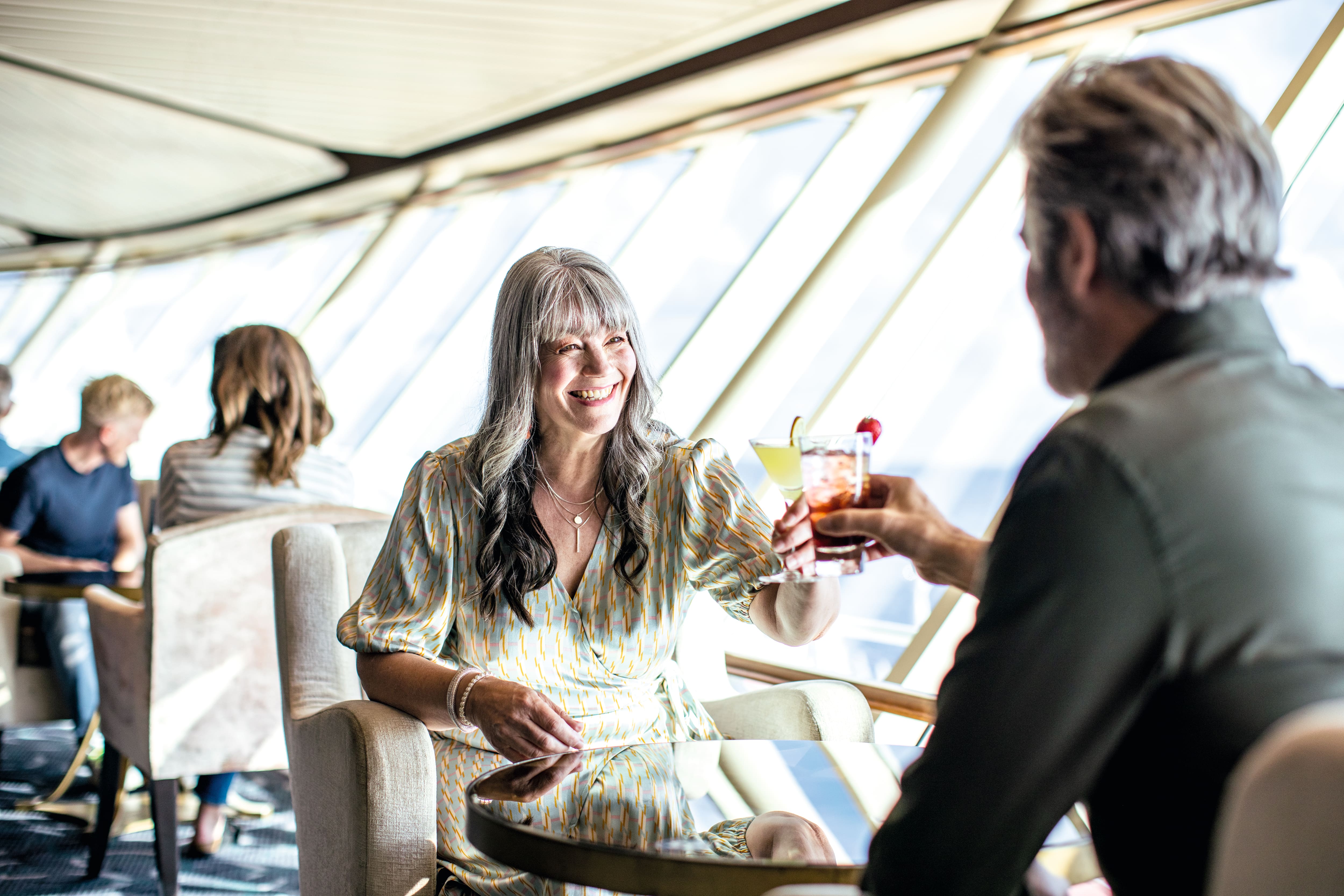 A couple holding up drinks in a restaurant on a Marella cruise ship.