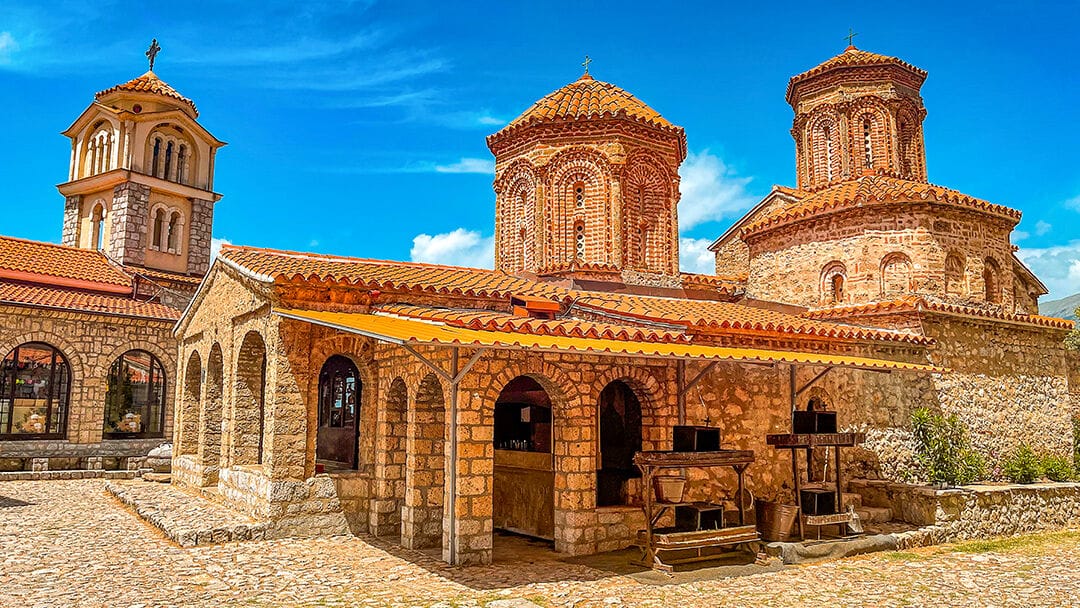 An orange stone and tile monastery with blue skies in the background