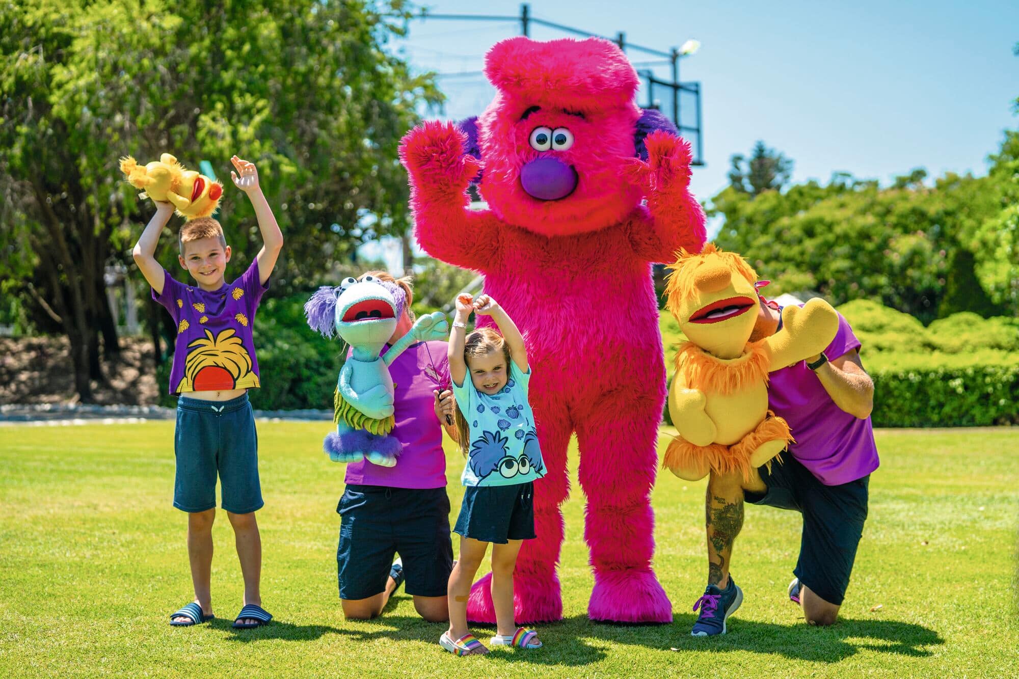 Children playing with Russell the Brussel mascot.