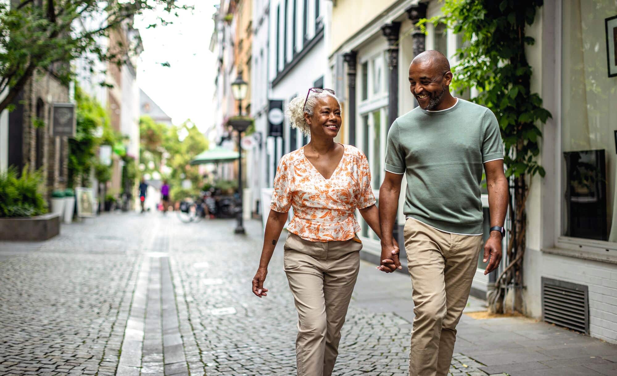 A couple walking hand-in-hand on a cobbled street.