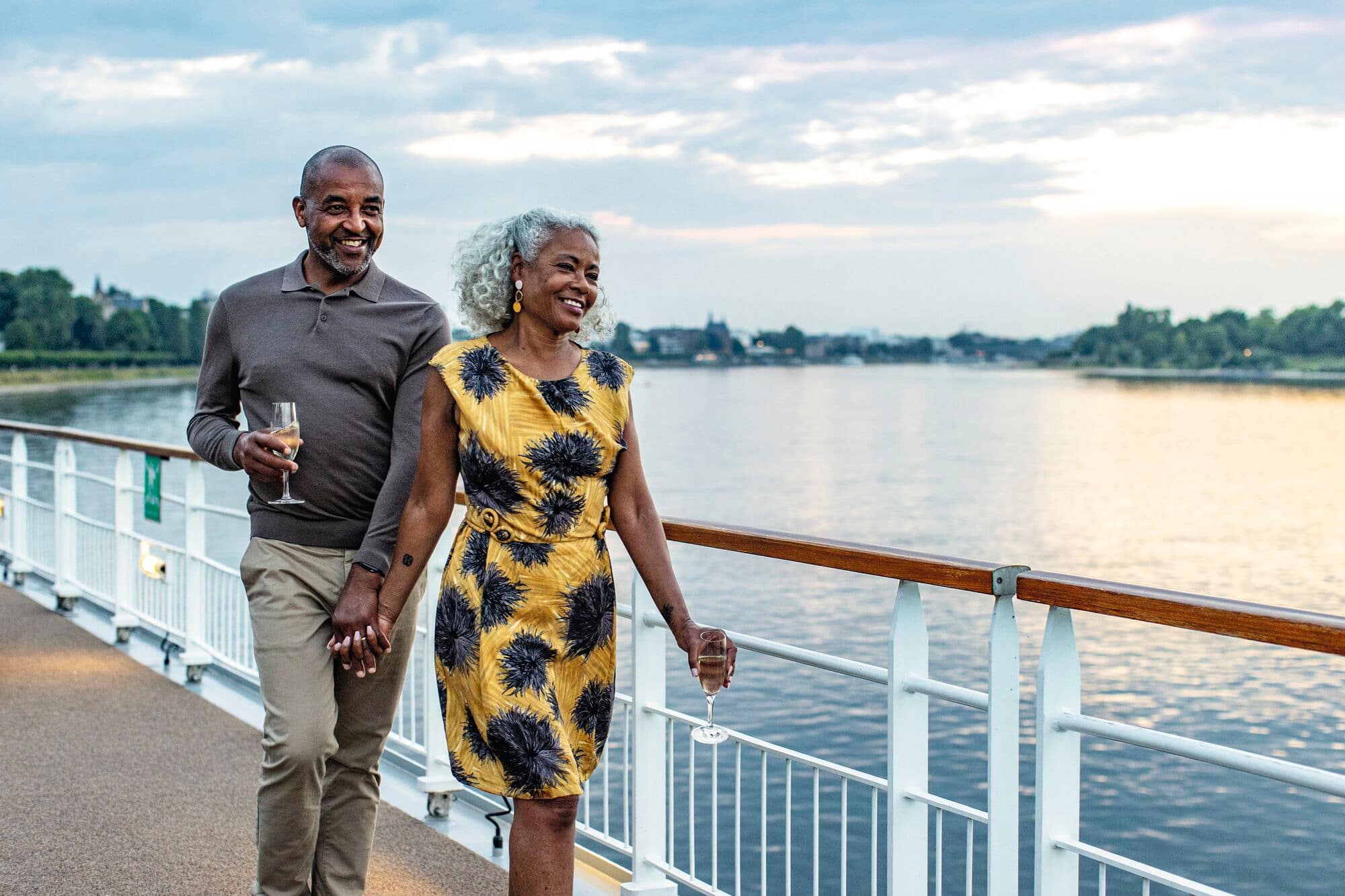 A couple holding hands and smiling on the deck of the ship.