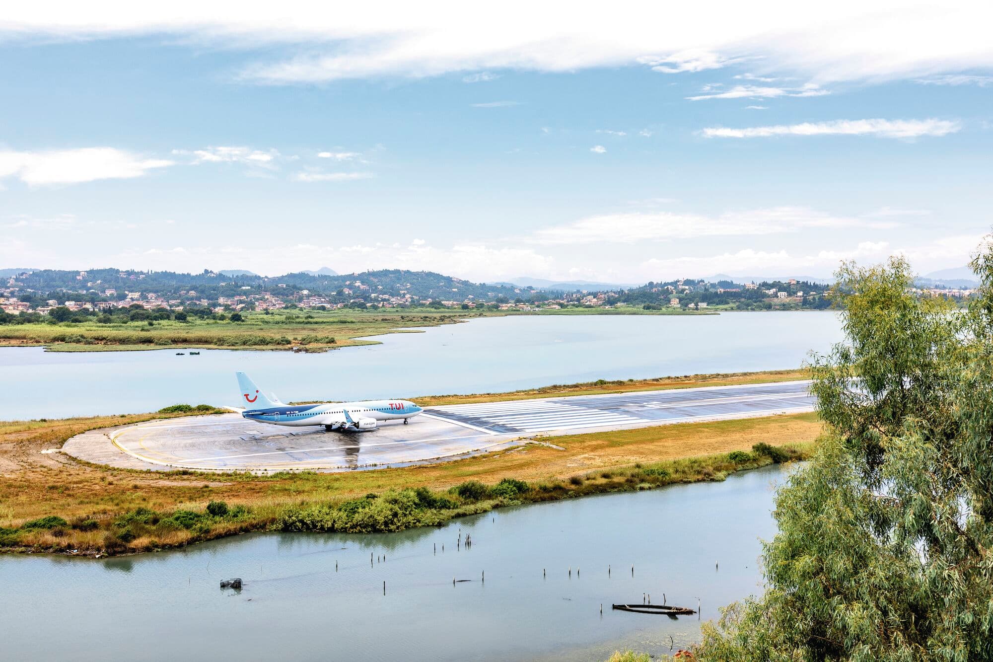 A plane on a landing strip surrounded by green fields.