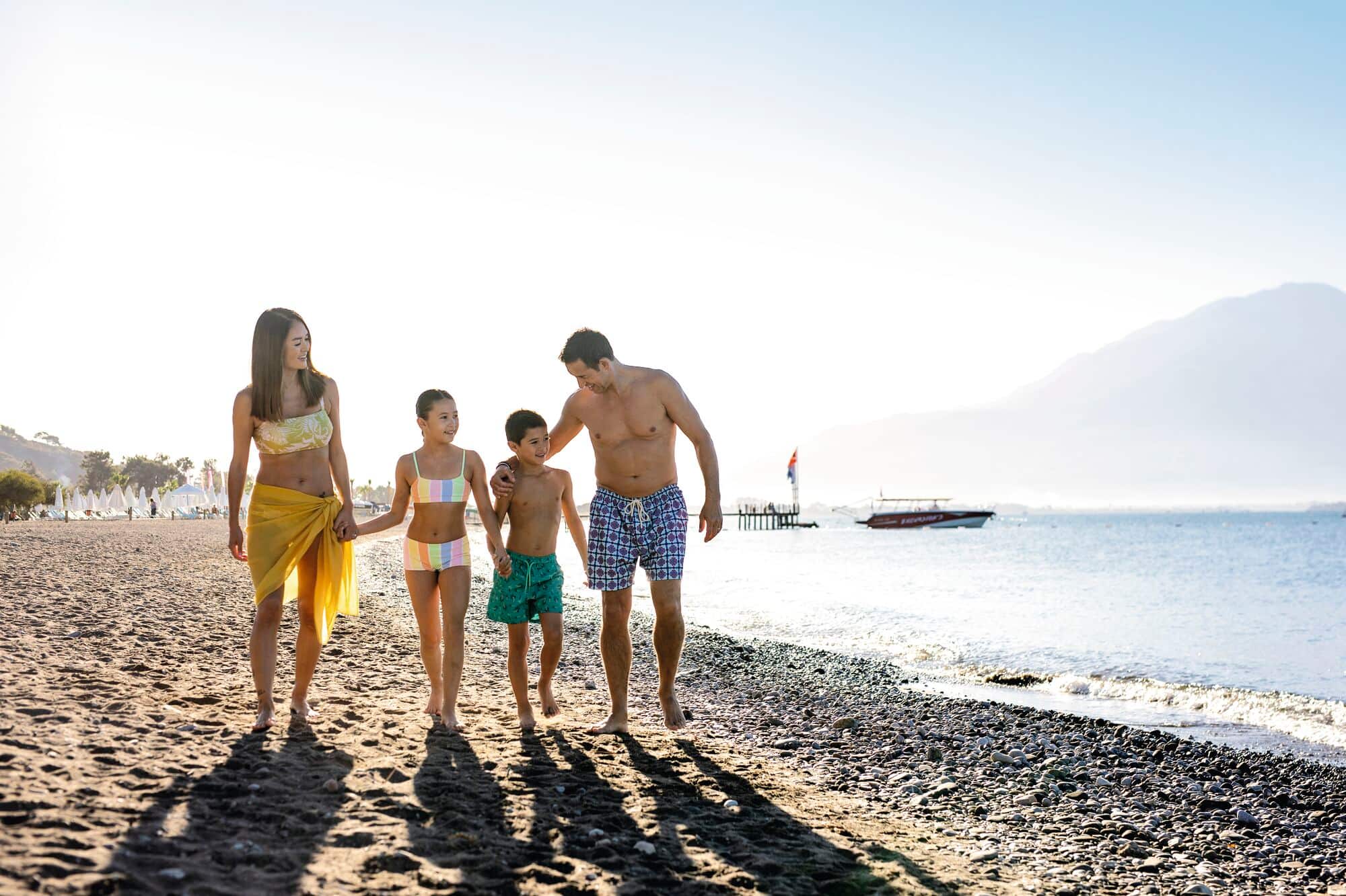 A family of four walking on the beach.