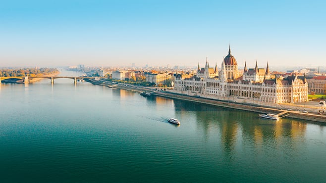 Ariel view of large river looking over to Budapest Parliament building with autumn sun 