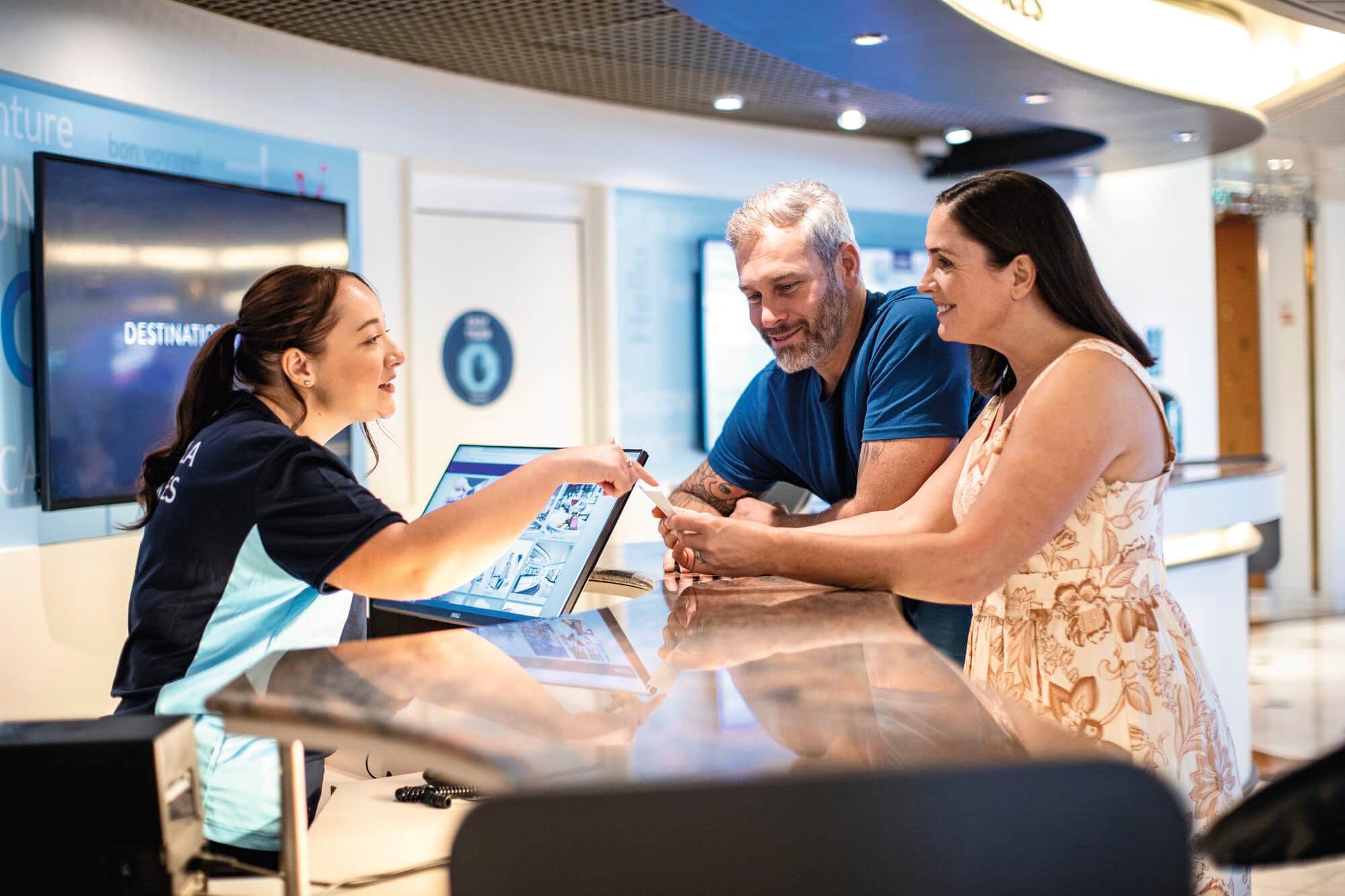 A couple being assisted by Marella staff at a help desk.