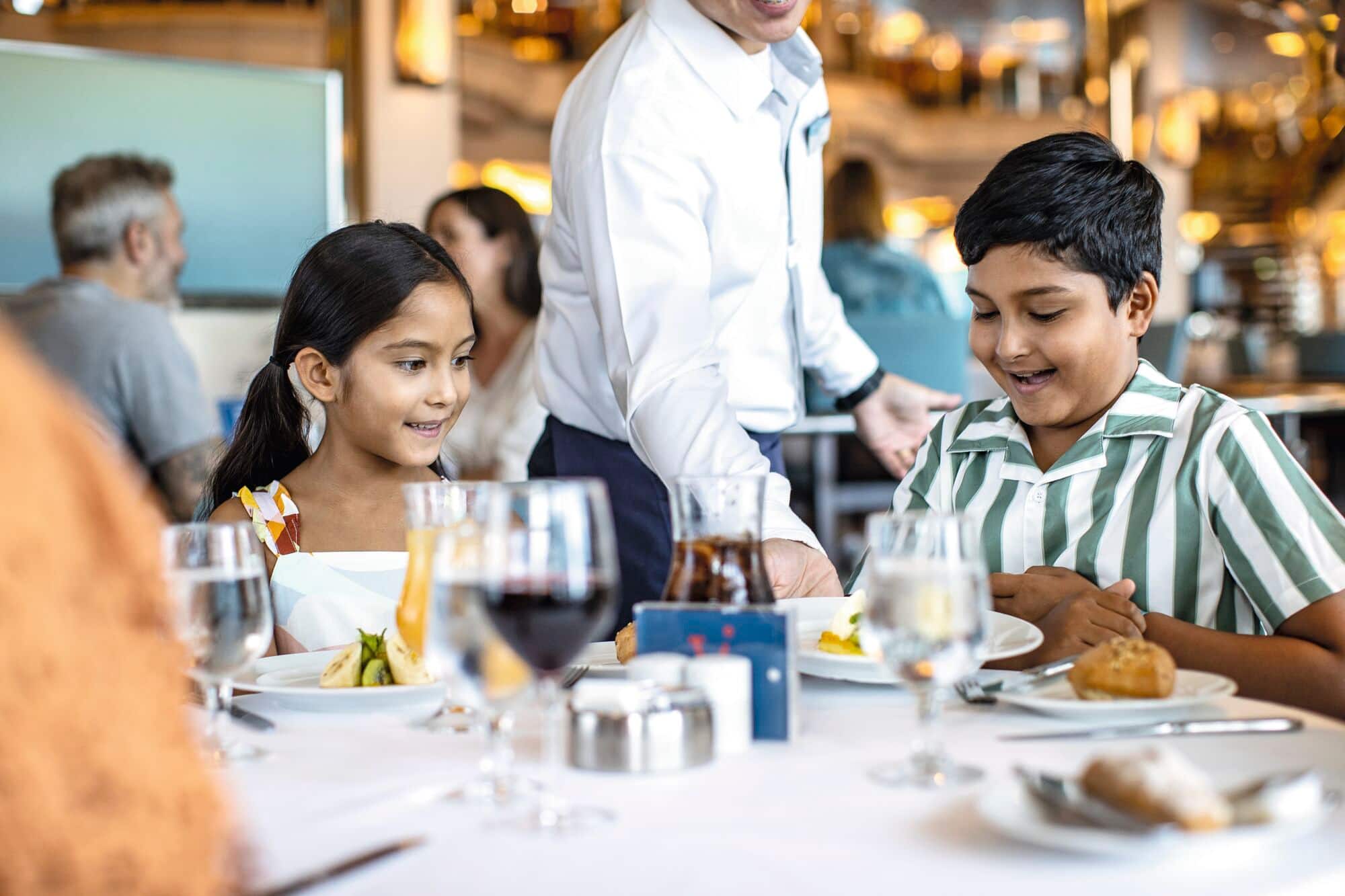 Two children smiling at a dinner table.