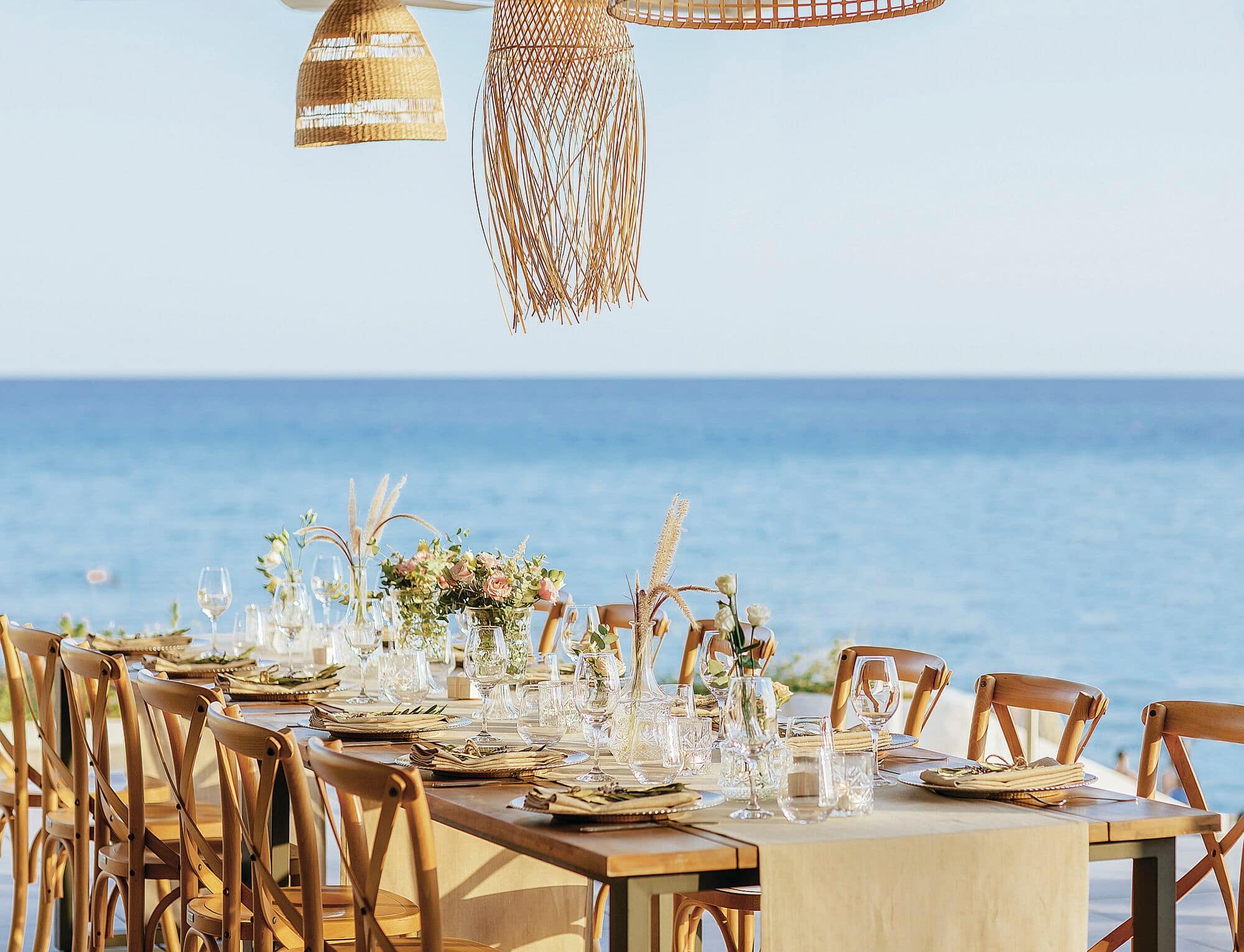 Rustic, yet contemporary decoration fills a table, set for a wedding dinner. Tropical details and an ocean view set an exotic tone.
