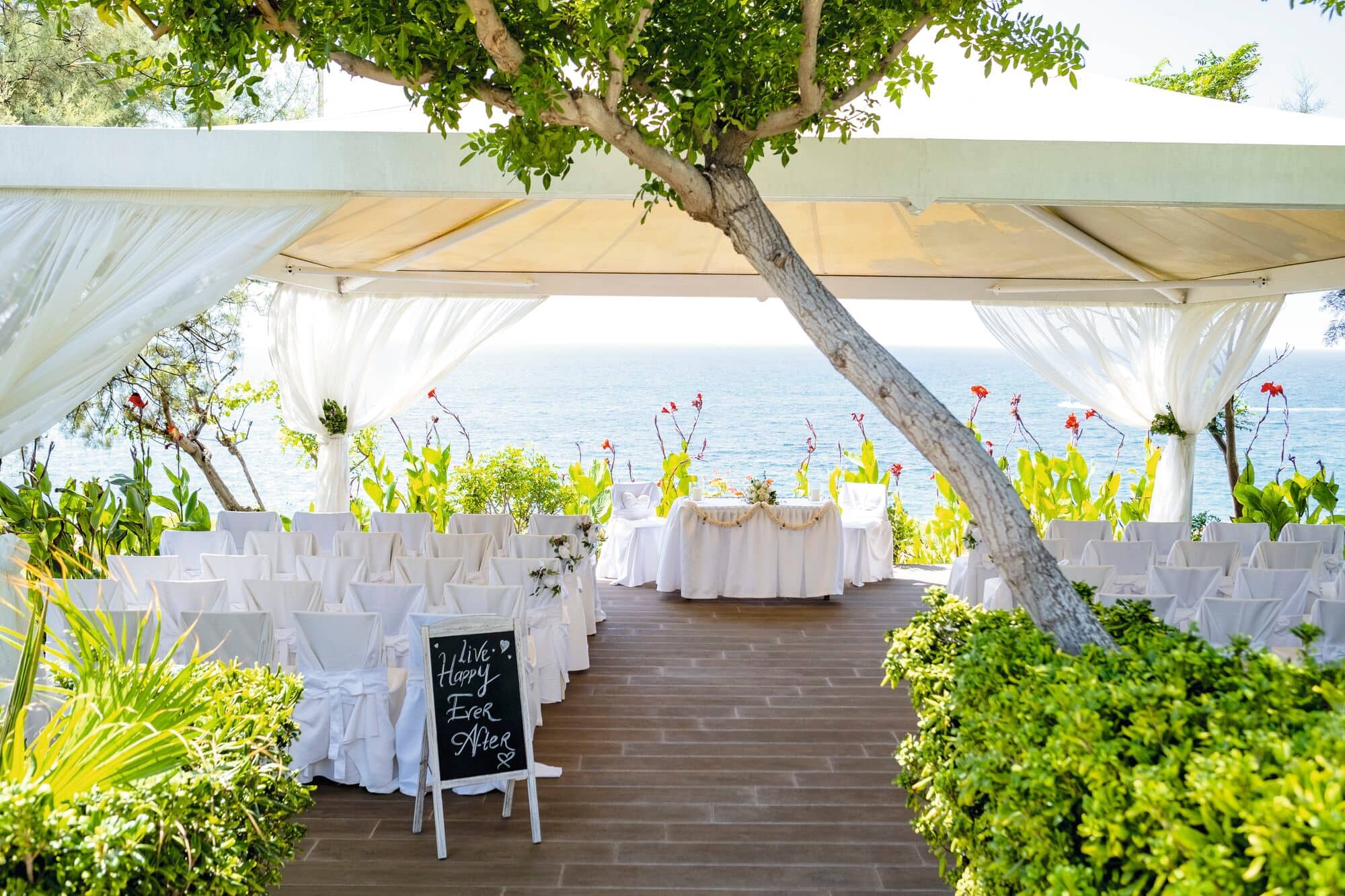 A wedding ceremony set up under a gazebo in secluded gardens.