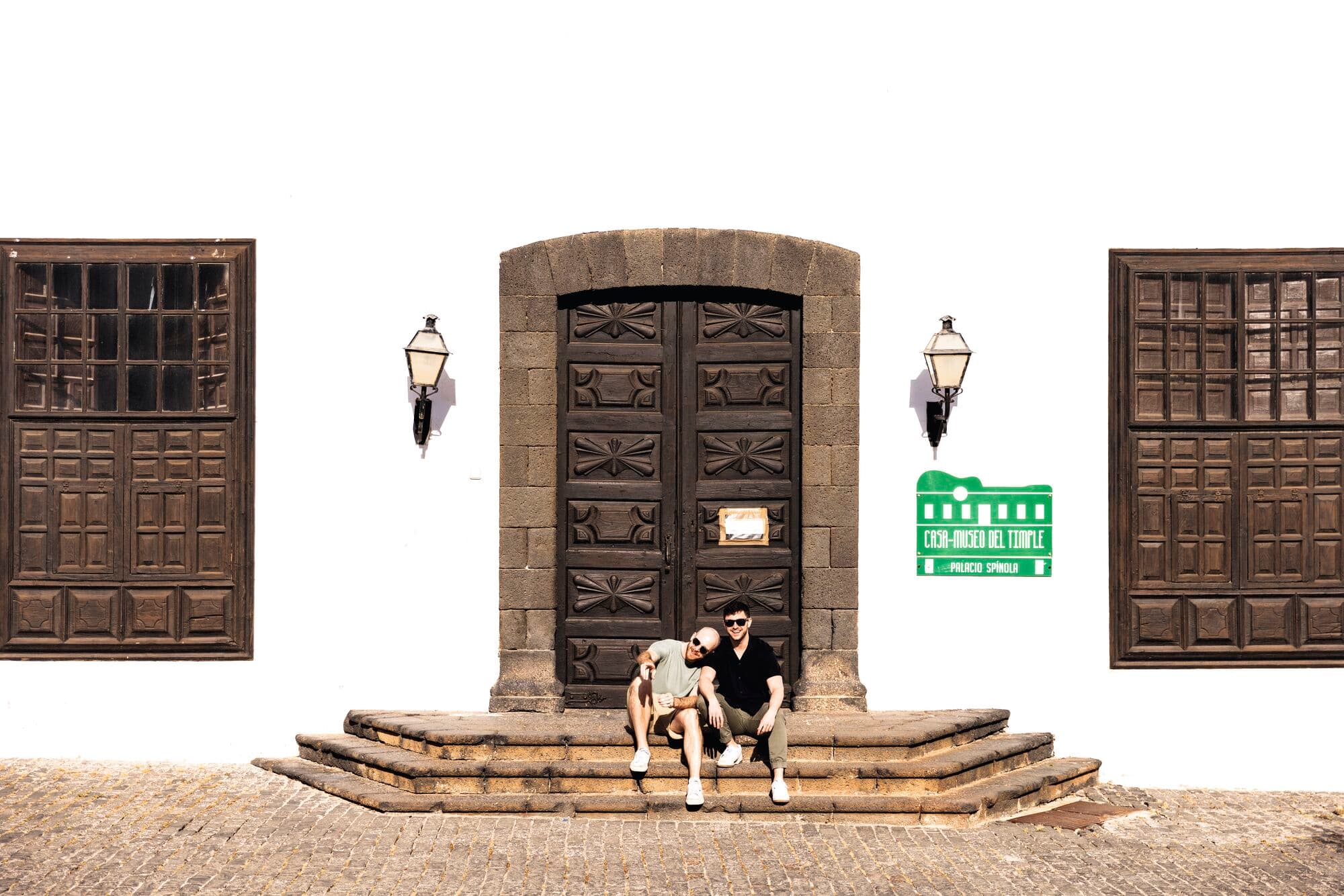 Two people sat on stone steps embracing outside a building.
