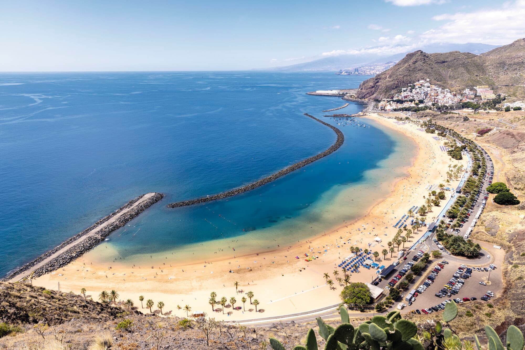A aerial view of a crescent-shaped beach with turquoise water.