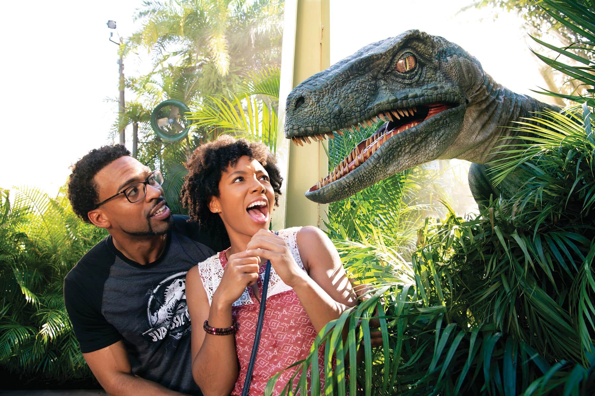 Coaster speeds past a roaring velociraptor – prehistoric thrills and theme park fun collide.