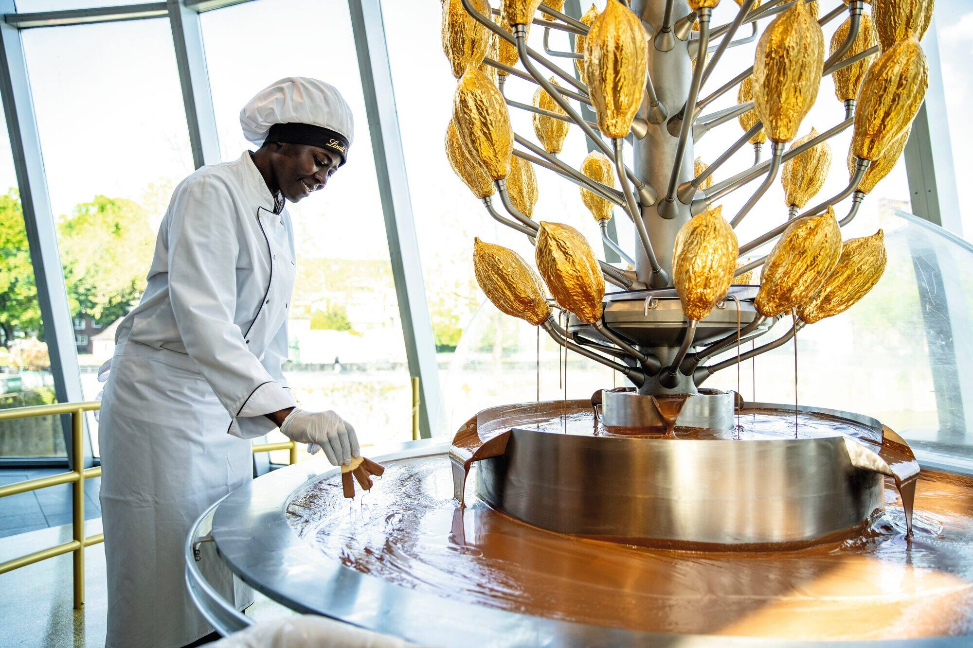 A person dipping biscuits into a chocolate fountain at the Cologne chocolate museum.