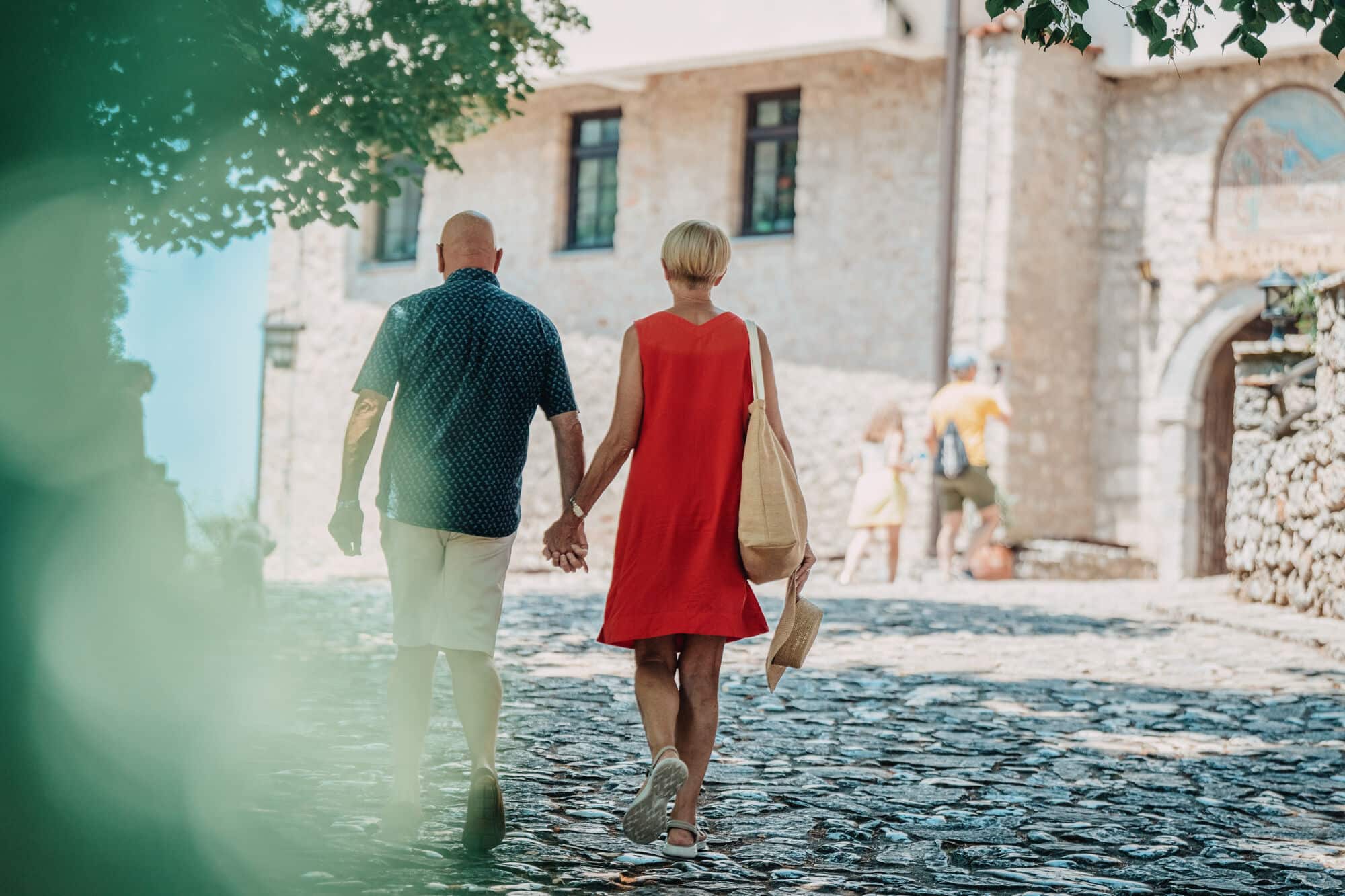 A couple walk hand in hand through the cente of Ohrid. The sun is shining. 