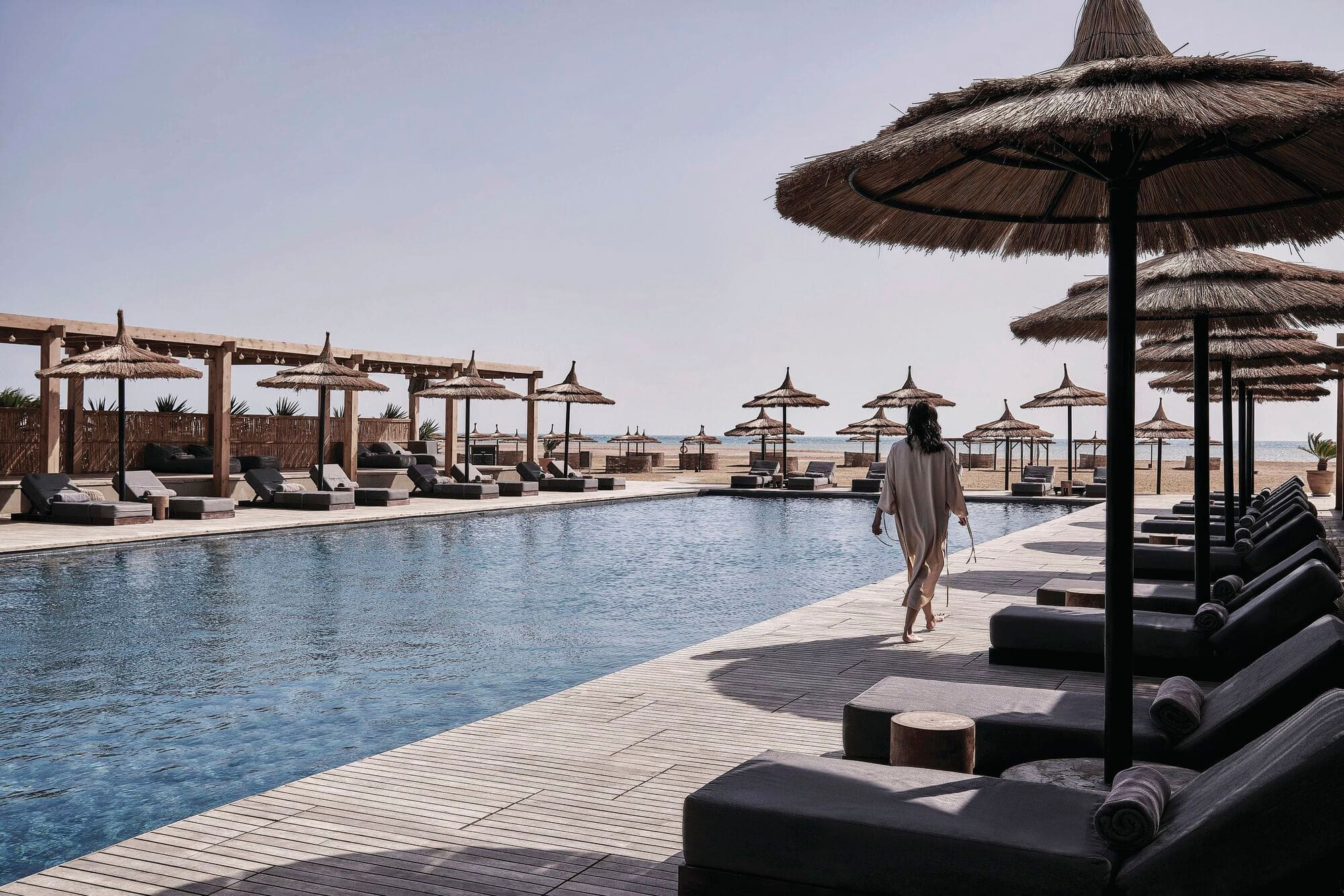 A woman walking along a hotel pool.