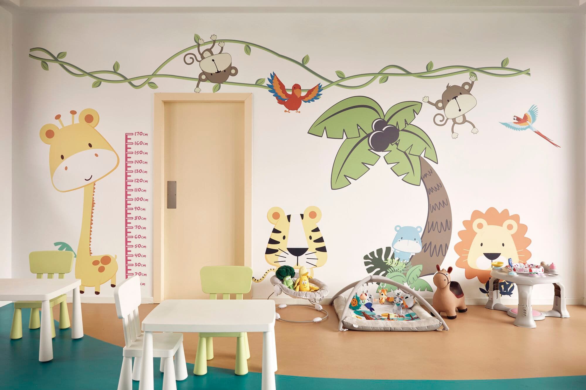 A baby and toddler room with a cartoon animal mural on the wall.