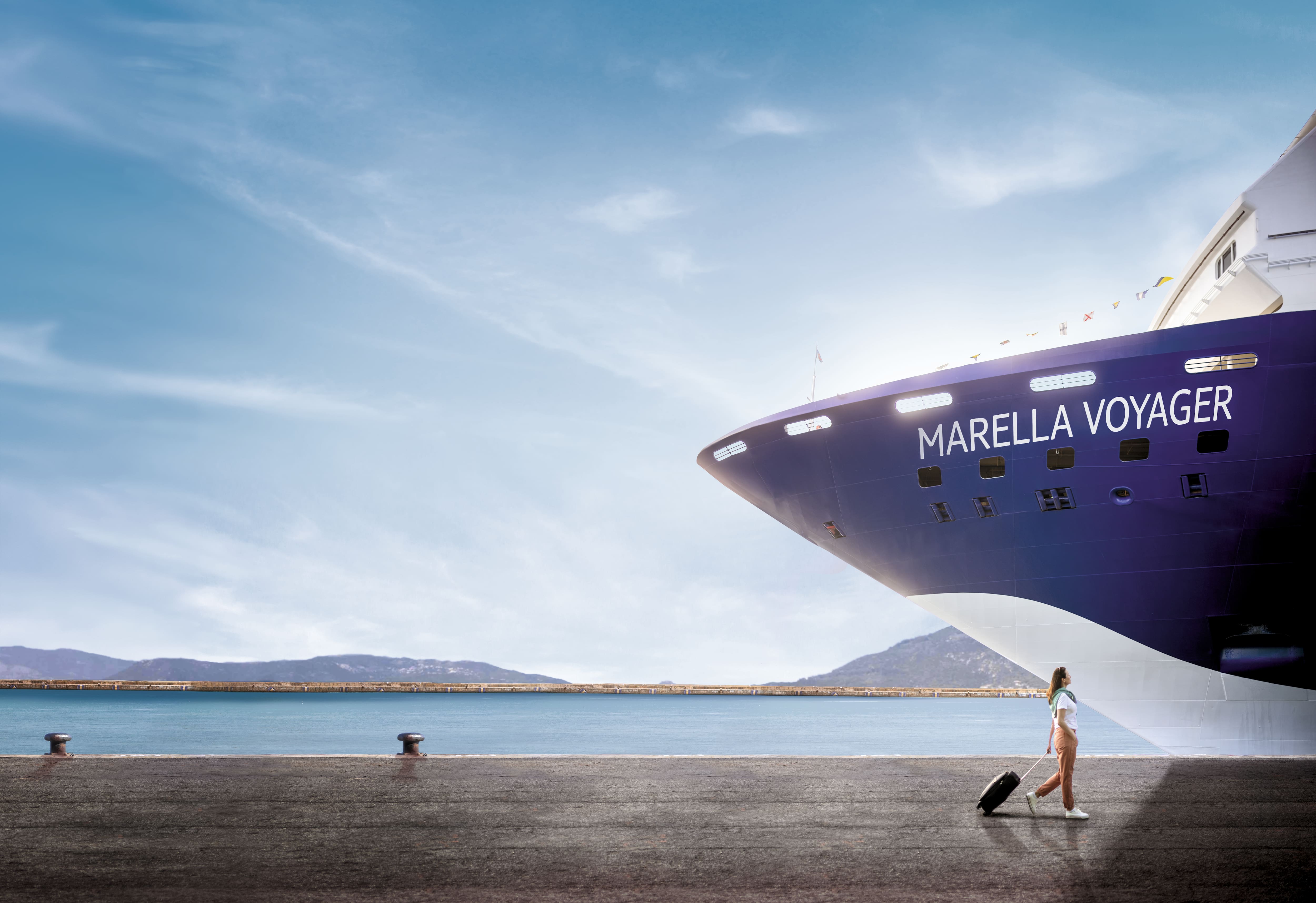 A woman pulling along a suitcase by a Marella Ship.