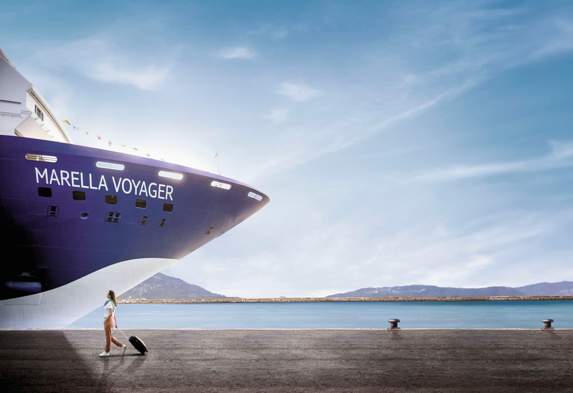 A woman pulling a suitcase in front of a Marella Cruise ship.