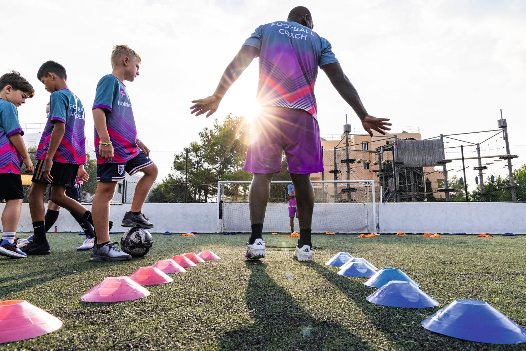 A coach from the football academy carrying out a football drill.